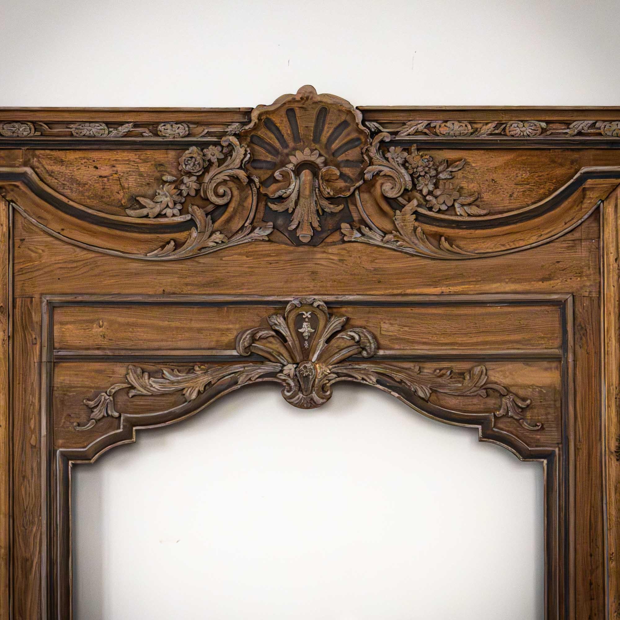 Large baroque fireplace surround of oak wood with carved and patinated floral bouquets, rocailles as well as central shell decoration with volutes and leaf tendrils. Total height: 242.5 cm; height of cornice: 124.5 cm; cut-out for mirror: 55 x 88