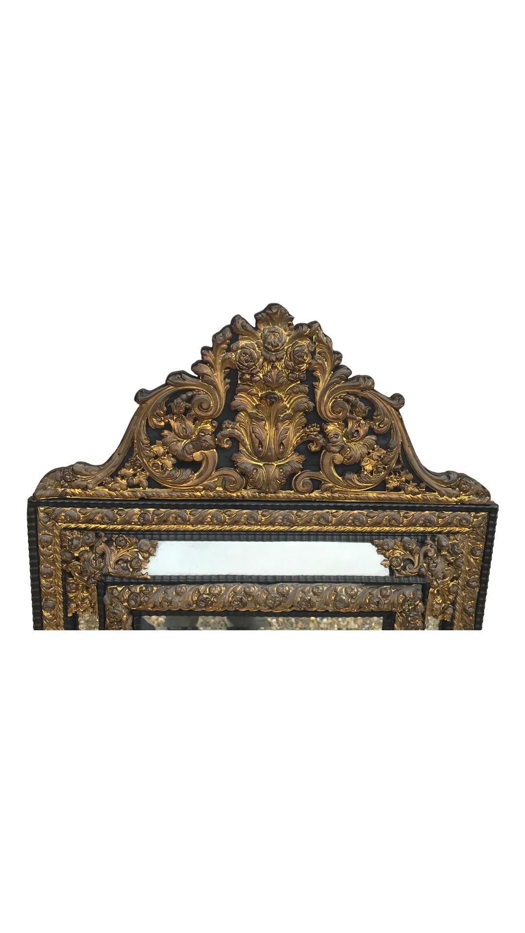 This beautiful unique Baroque mirror was made in the 18th-19th century in Belgium. The frame features a hammered brass decor with flower and acanthus leave motifs. The mirror glass is original. The wall mirror is in good original condition. It is a