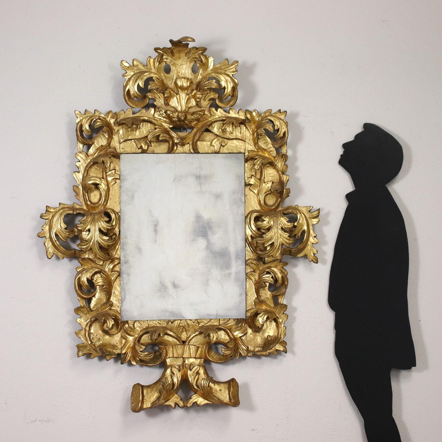 Baroque mirror, the frame is carved with powerful leafy volutes, it is entirely gilded; with lacks and restorations.