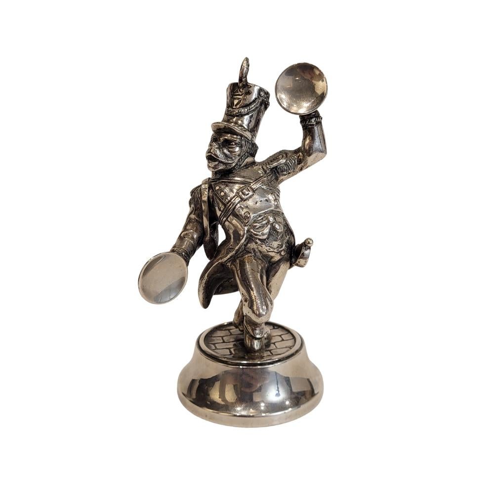 Raffinata e bellissima statuetta in argento che raffigura una scimmia musicista vestita in uniforme militare. L'uniforme militare comprende una fascia sul petto, una spada al fianco e un fucile a pompa sulla spalla, oltre all'alto cappello in stile
