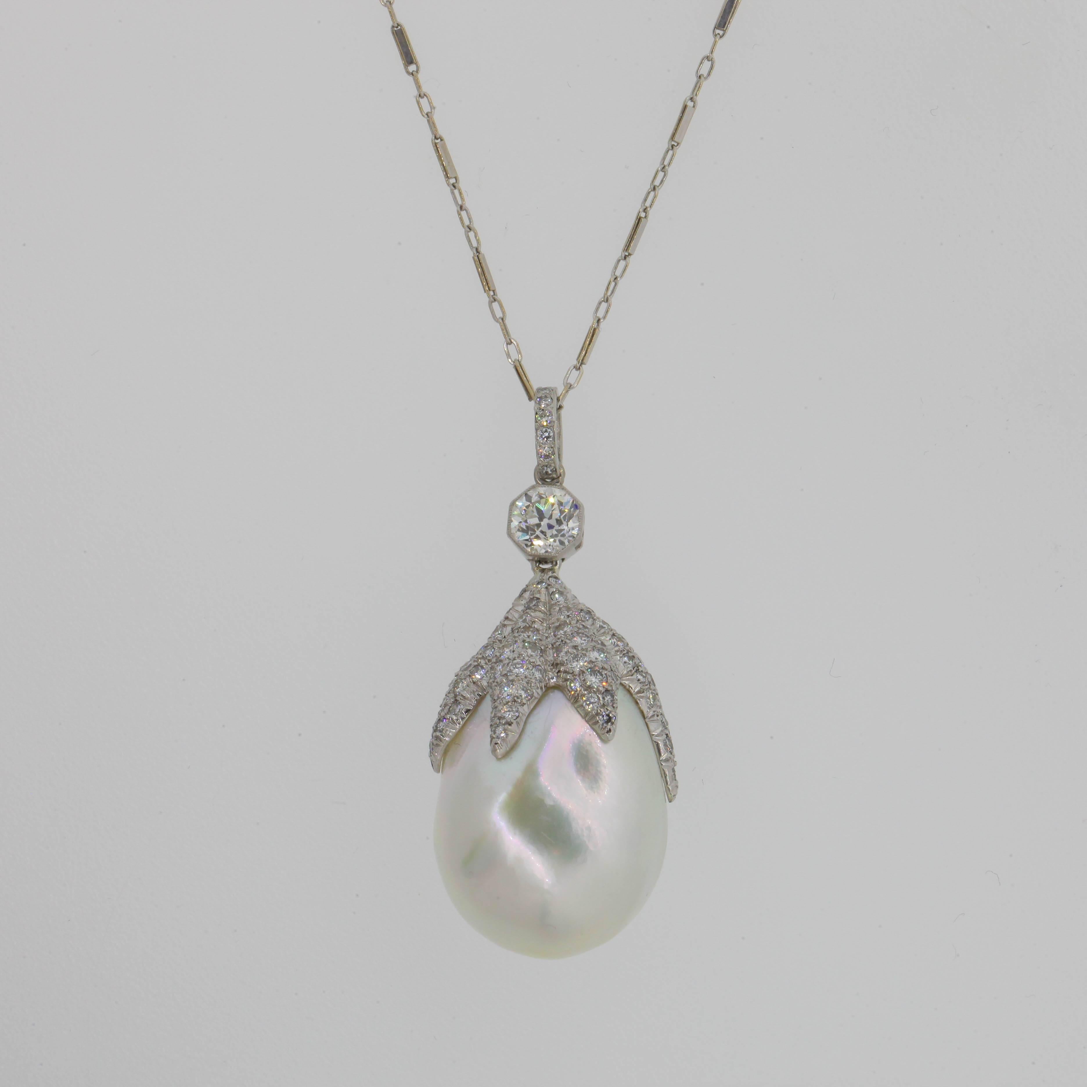 A one of a kind  26 x 19.5 mm large Baroque Pearl with rainbow overtones.  This lustrous Pearl is set with a six branch pave cap dangling from a bezel set 0.88 carat Old European Cut Diamond.  Circa 1970s.