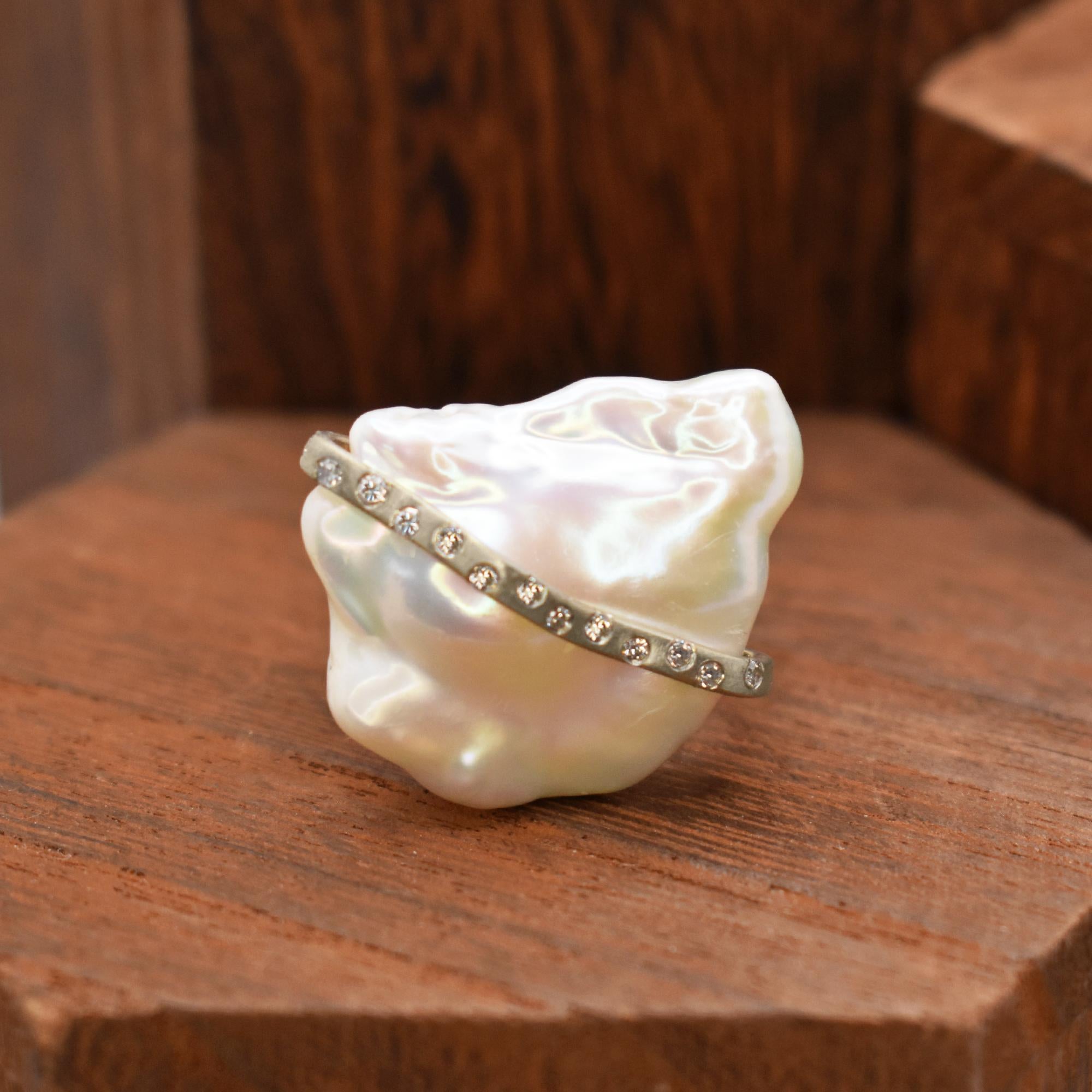Magnifique perle baroque d'eau douce enveloppée dans une rivière d'argent sterling avec des diamants en accent. L'anneau carré en argent sterling mesure 12 mm de large et correspond à une taille 7, mais peut être redimensionné. Le métal argenté est