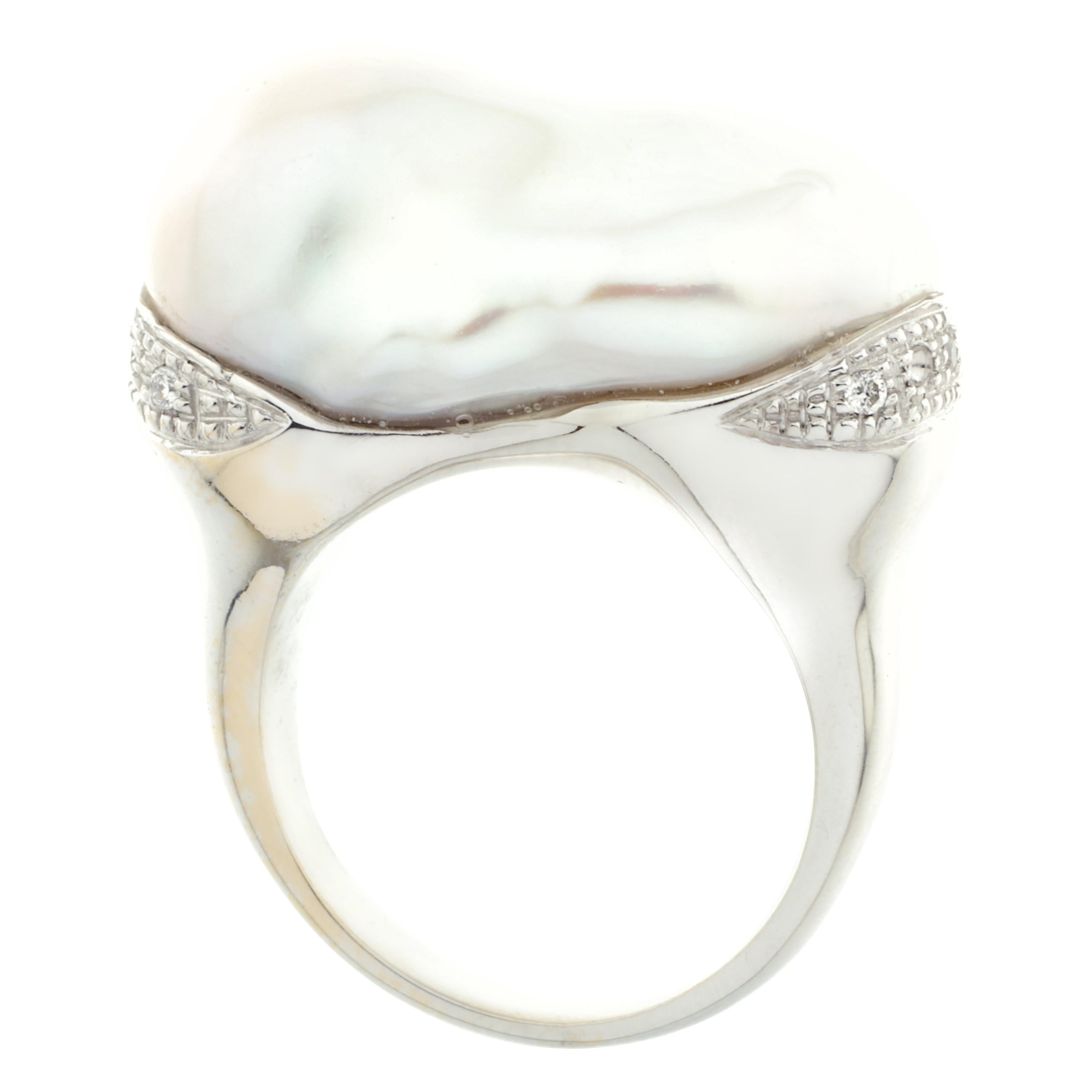 A stunning cocktail ring masterfully created entirely by hand from 18-karat white gold. Featuring a large cultured pearl set with ten white diamonds rated G VS which 