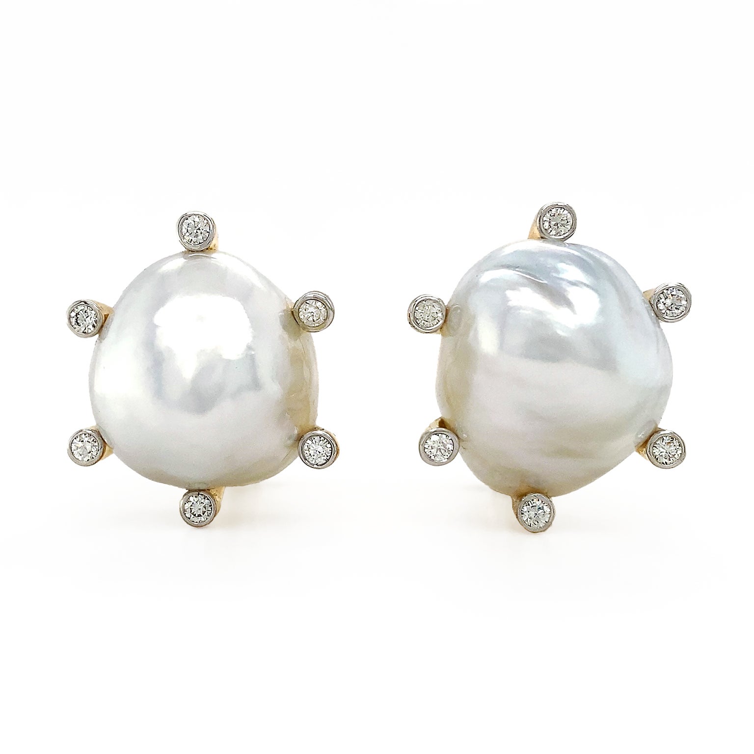 A polychromatic glow is created by these earrings. At the center is a single white baroque pearl, capturing depth and reflecting an array of light. 18k yellow gold prongs adorned with brilliant cut diamonds secure the pearl. The diamonds produce