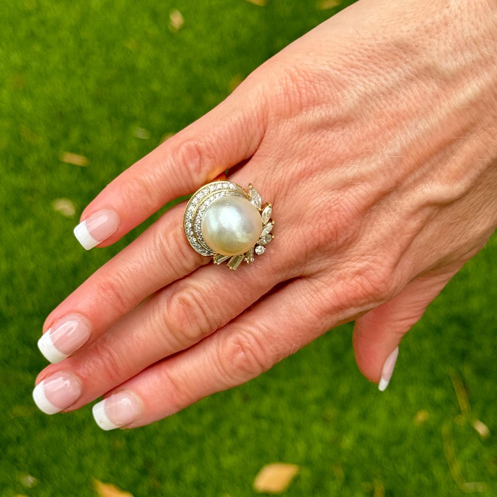 This beautiful baroque pearl diamond cocktail ring is a stunning piece of jewelry, crafted in 18 karat yellow gold, that exudes vintage charm and sophistication. At the center of the ring sits a 16mm white baroque pearl, renowned for its unique and