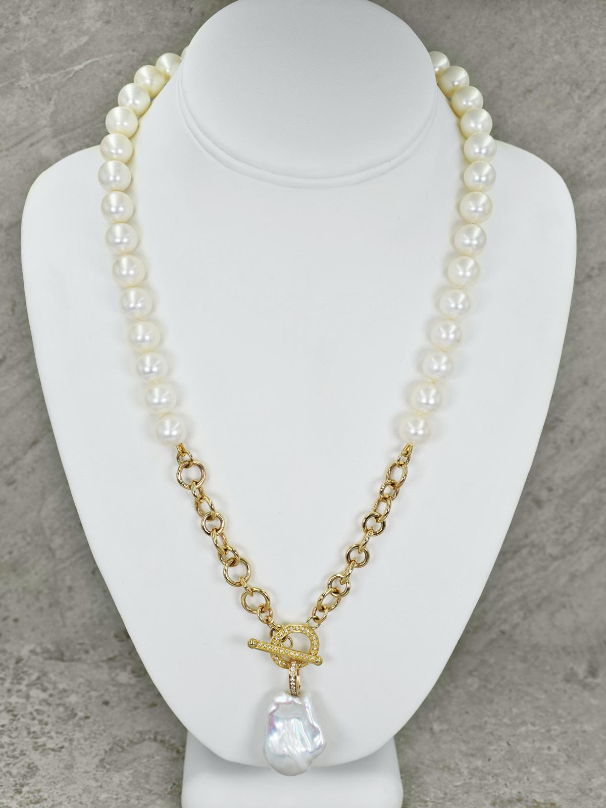 Gorgeous, large Freshwater Baroque Pearl and accent white diamond 14k yellow gold enhancer pendant on a knotted, 11mm round white freshwater pearl beaded necklace. Necklace features a 14k gold chain and a double sided, diamond set toggle closure.