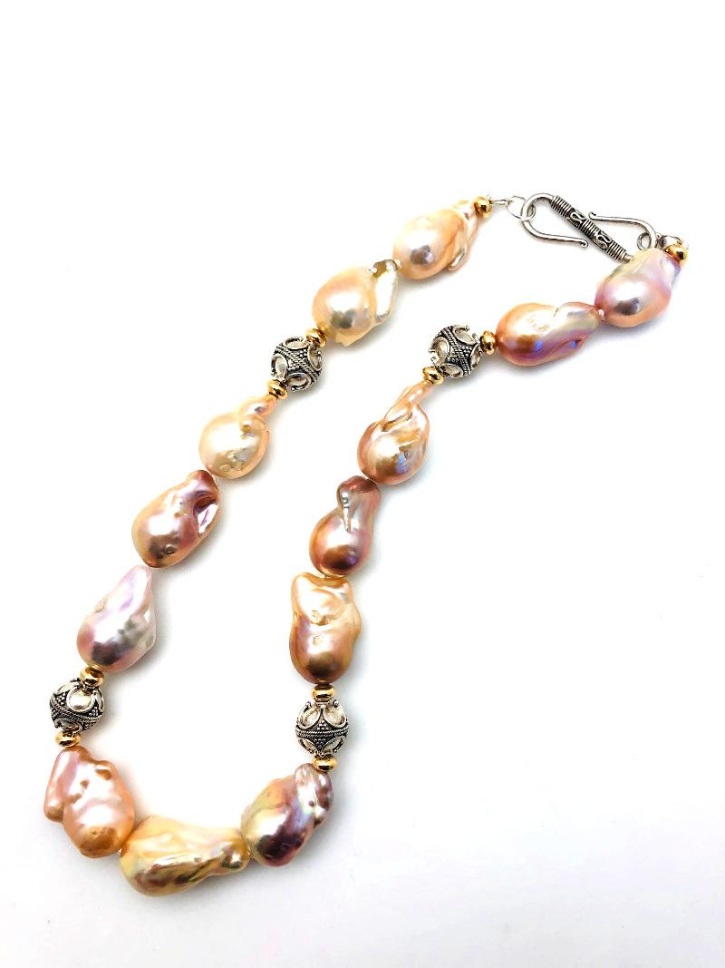 This gorgeous strand of baroque pearls is large and lustrous! The strand features iridescent cream-colored pearls with striking pink and golden overtones. The baroque (freeform) pearls measure approximately 3/4