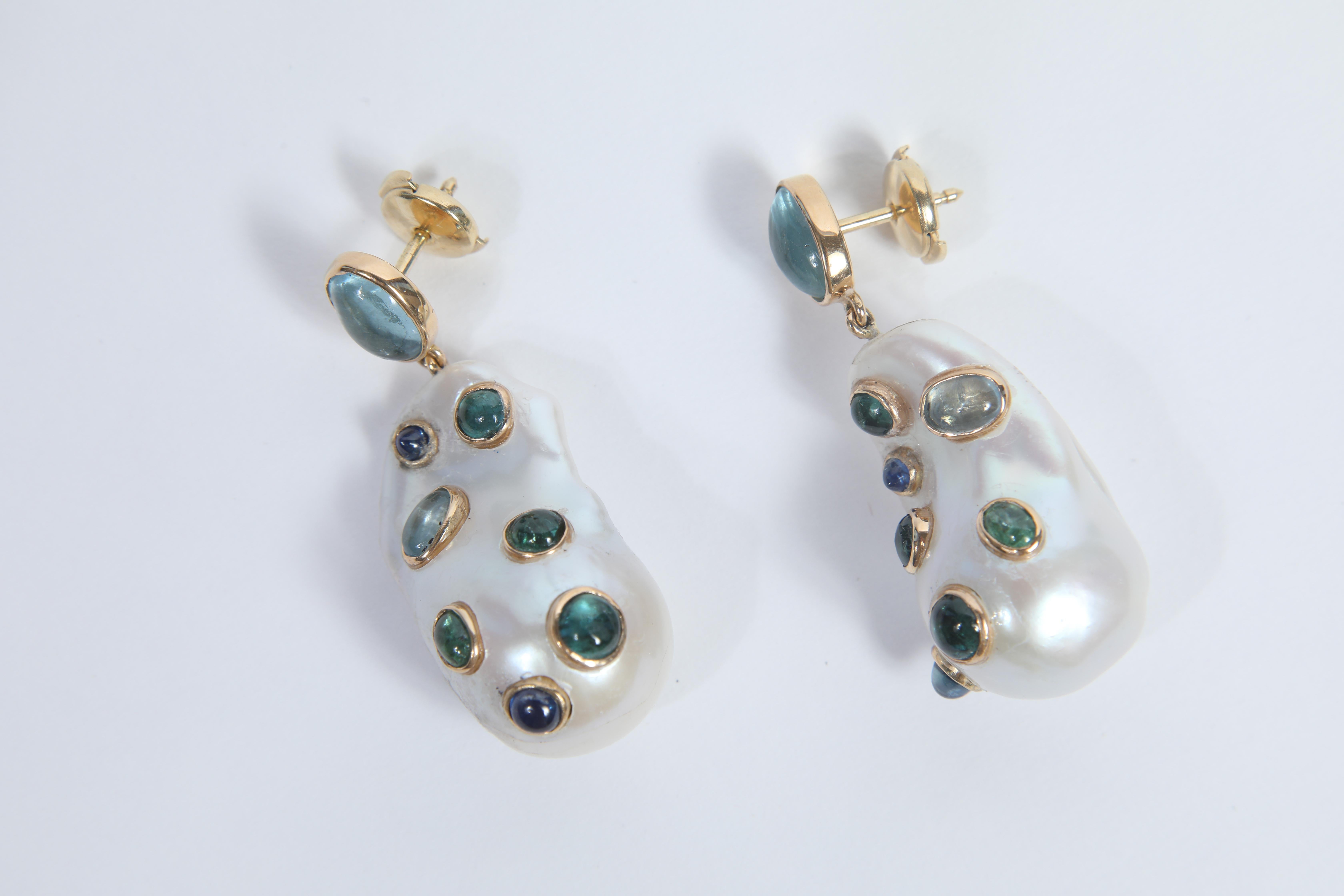 White fresh water pearls earrings, baroque shape, attached to aquamarine cabochons and set with sapphires, green tourmalines and aquamarine cabochons.
18k yellow gold, security Alpa systems.
Price without local taxes
Four aquamarine cabs weight: