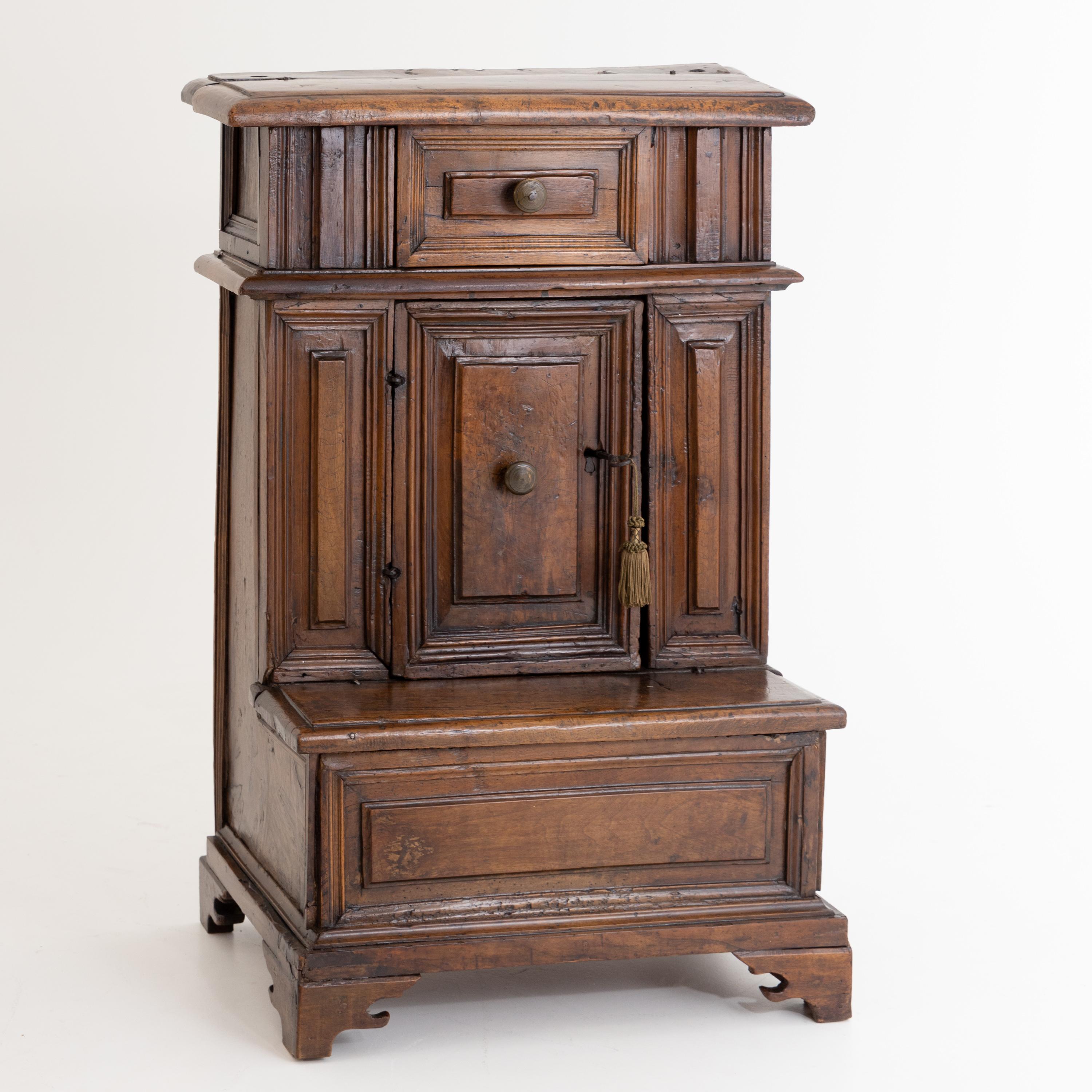 Prayer chair made of solid walnut with two chest compartments, a tabernacle compartment and one drawer; all sides with multi-profiled filling panels. Very beautiful patina.
 