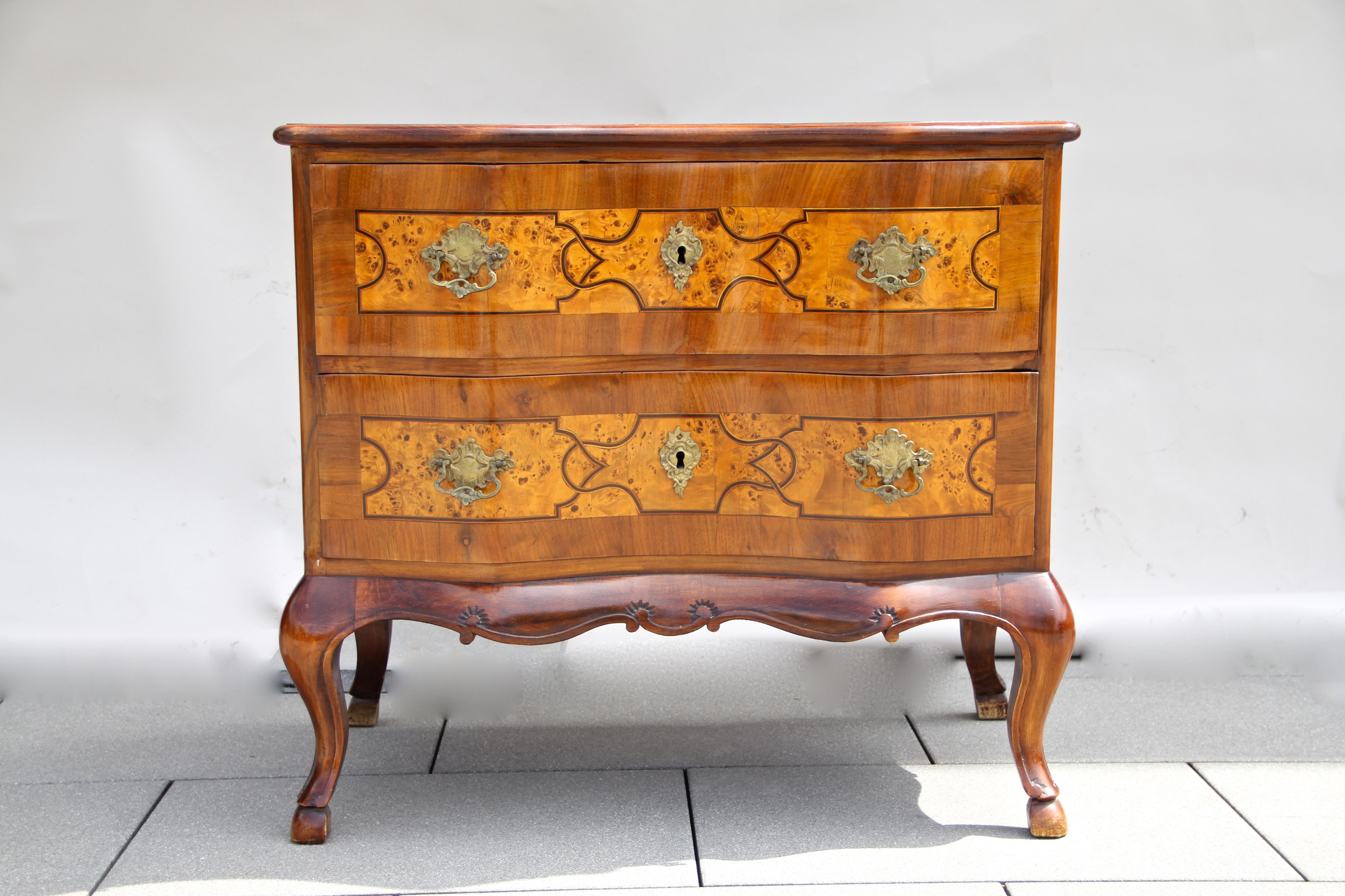 Unique Baroque Revival commode from circa 1890 in Austria. This mid-sized cabinet shows beautiful inlay works and comes with two gorgeous curved drawers. A great shaped hand carved base, wonderful brass fittings alongside a great designed marquetry