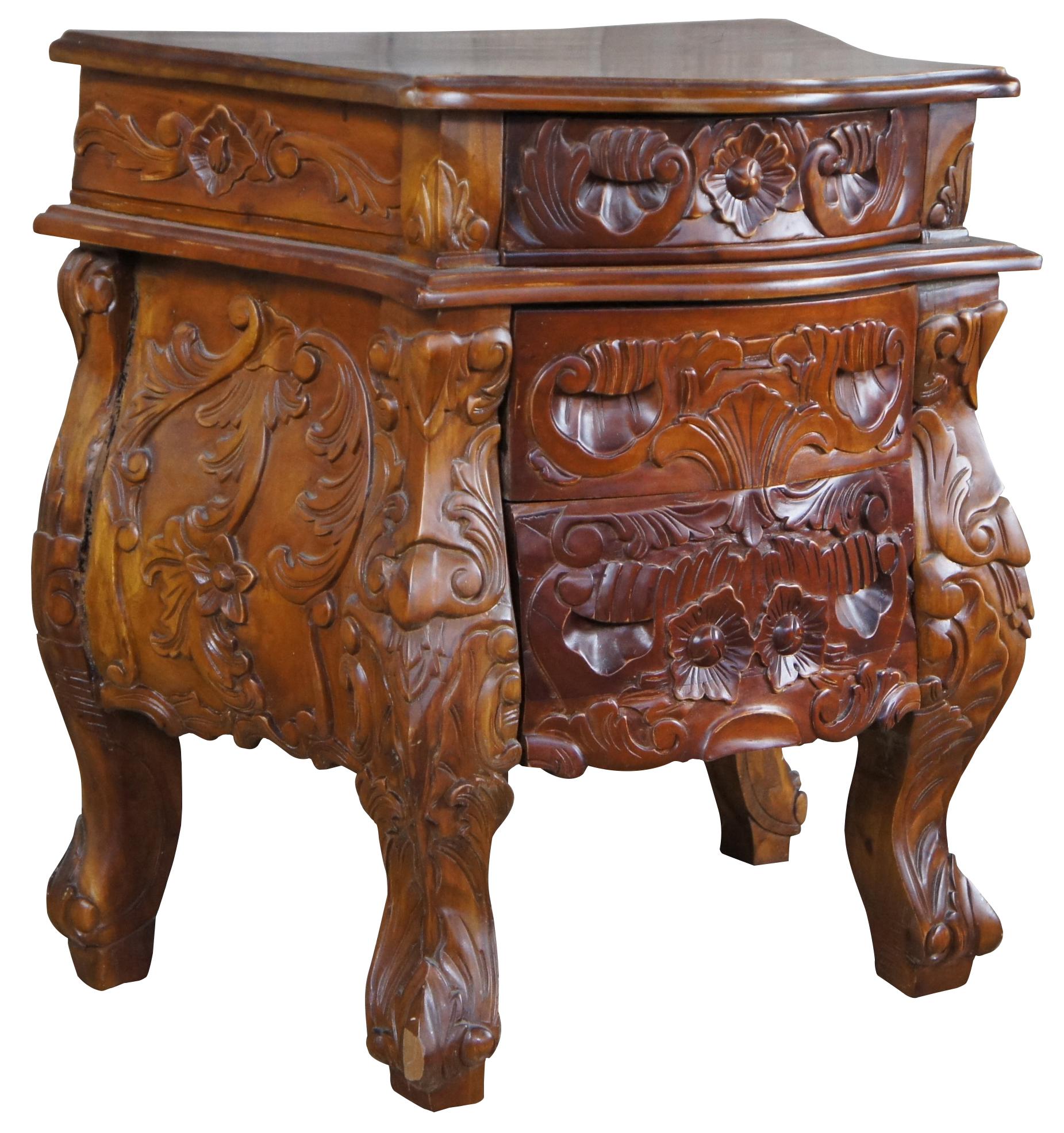 An elegant solid mahogany bedside or accent table. Rococo form with intricate floral and foliate carving. Features a serpentine top with three dovetailed drawers.
 