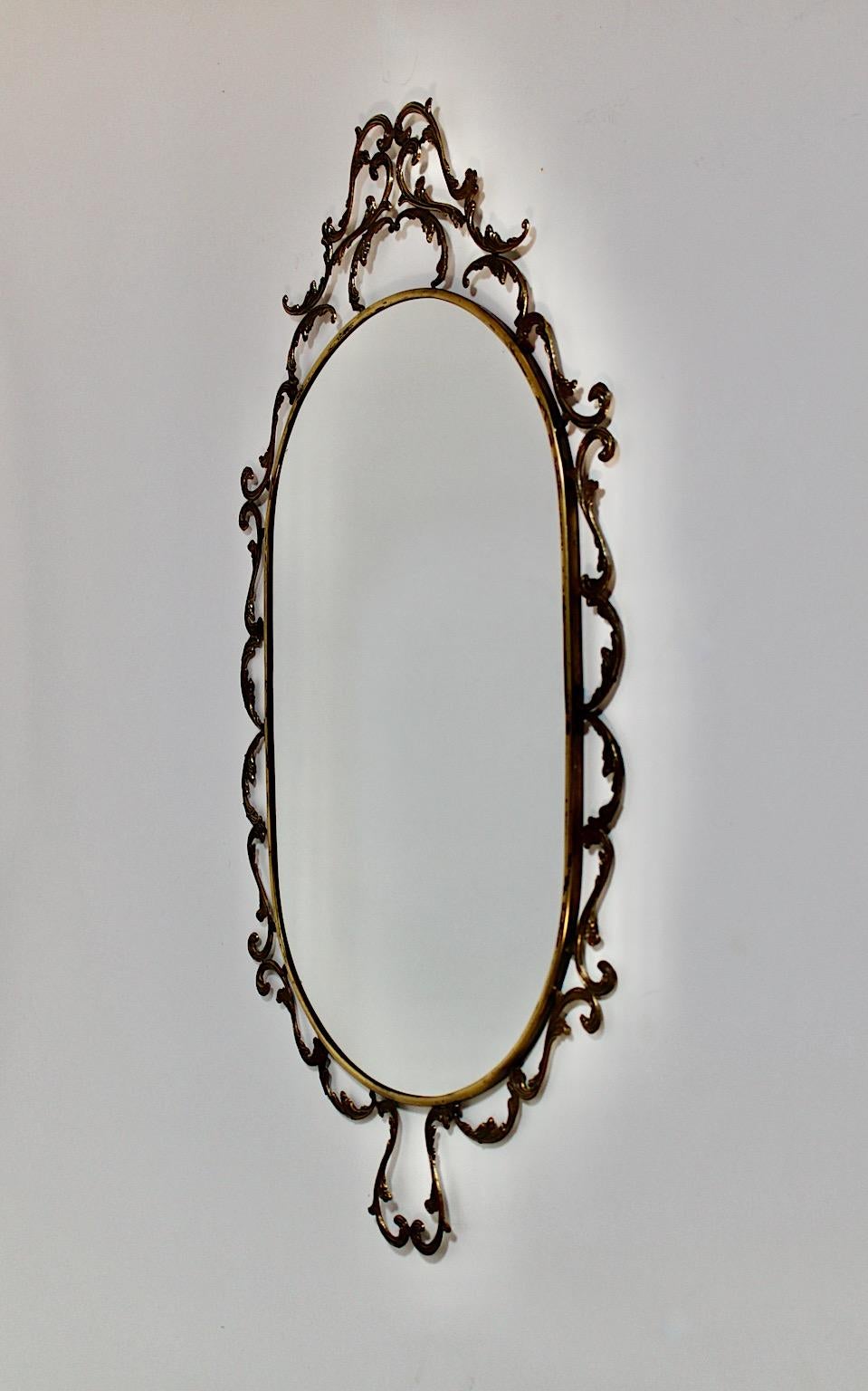 Baroque revival Style vintage oval wall mirror from brass partly blackened 1960s Italy.
A stunning and delicate baroque revival style wall mirror in oval form framed with wonderfully ornaments. This beautiful wall mirror shows an oval like mirror