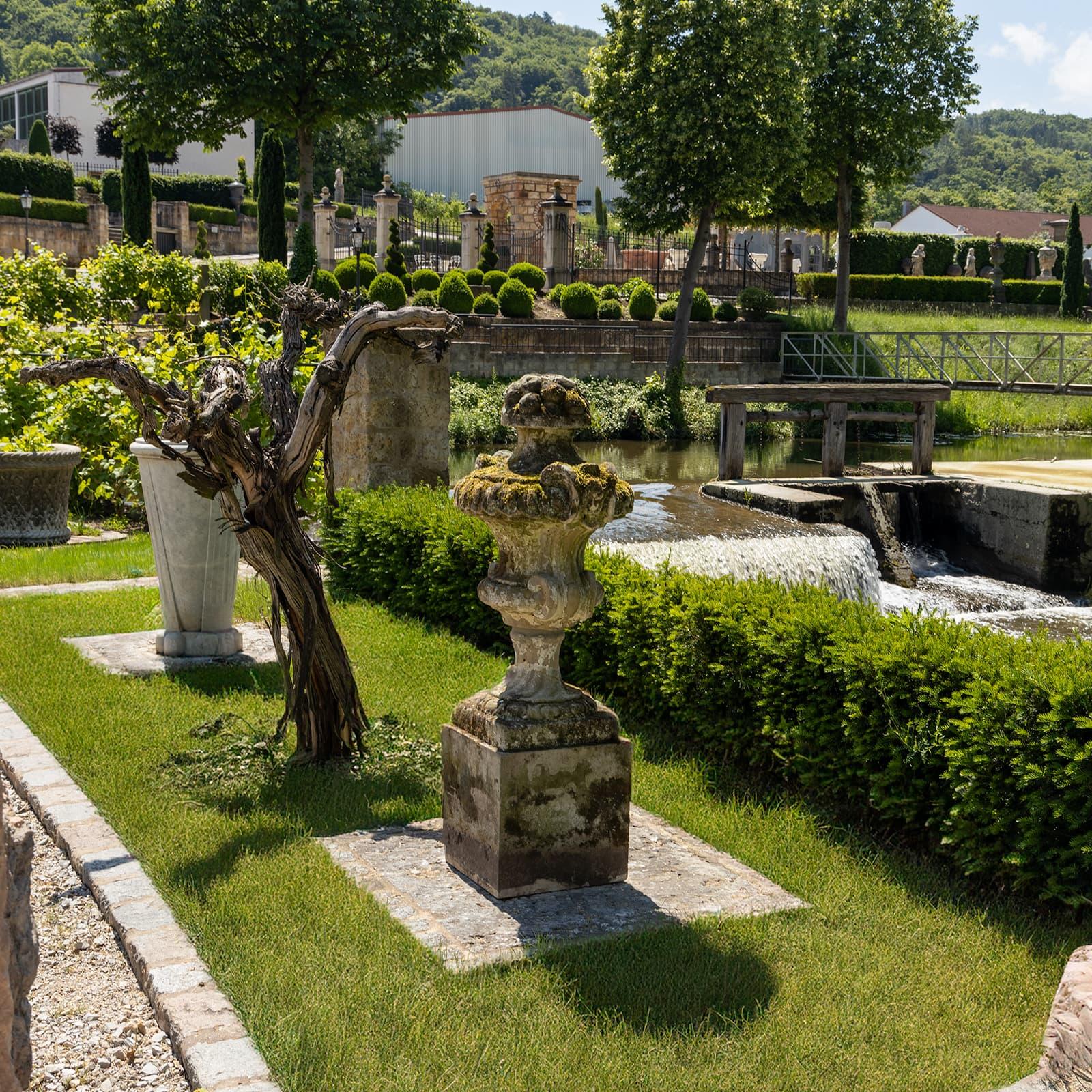 Grande urne baroque en grès avec des restes de peinture ancienne et une belle patine naturelle. L'urne est surmontée d'une corbeille de fruits et repose sur une base carrée en pierre. 