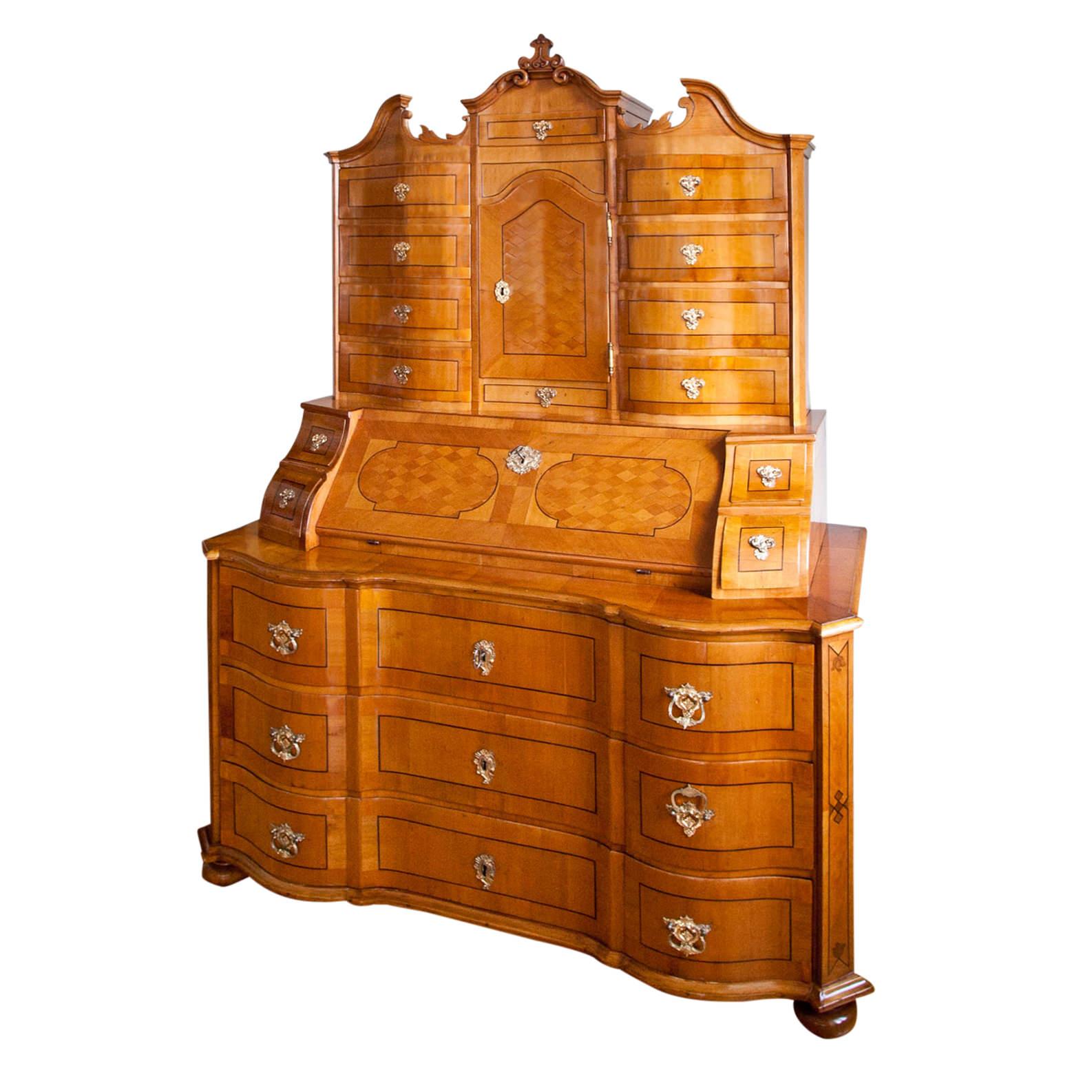 Large Baroque secretaire on bun feet with a three-drawer commode base with a serpentine front, a writing surface at a height of 80 cm and a broken pediment top part. The doors and drawers are decorated with thread inlays, the doors also with