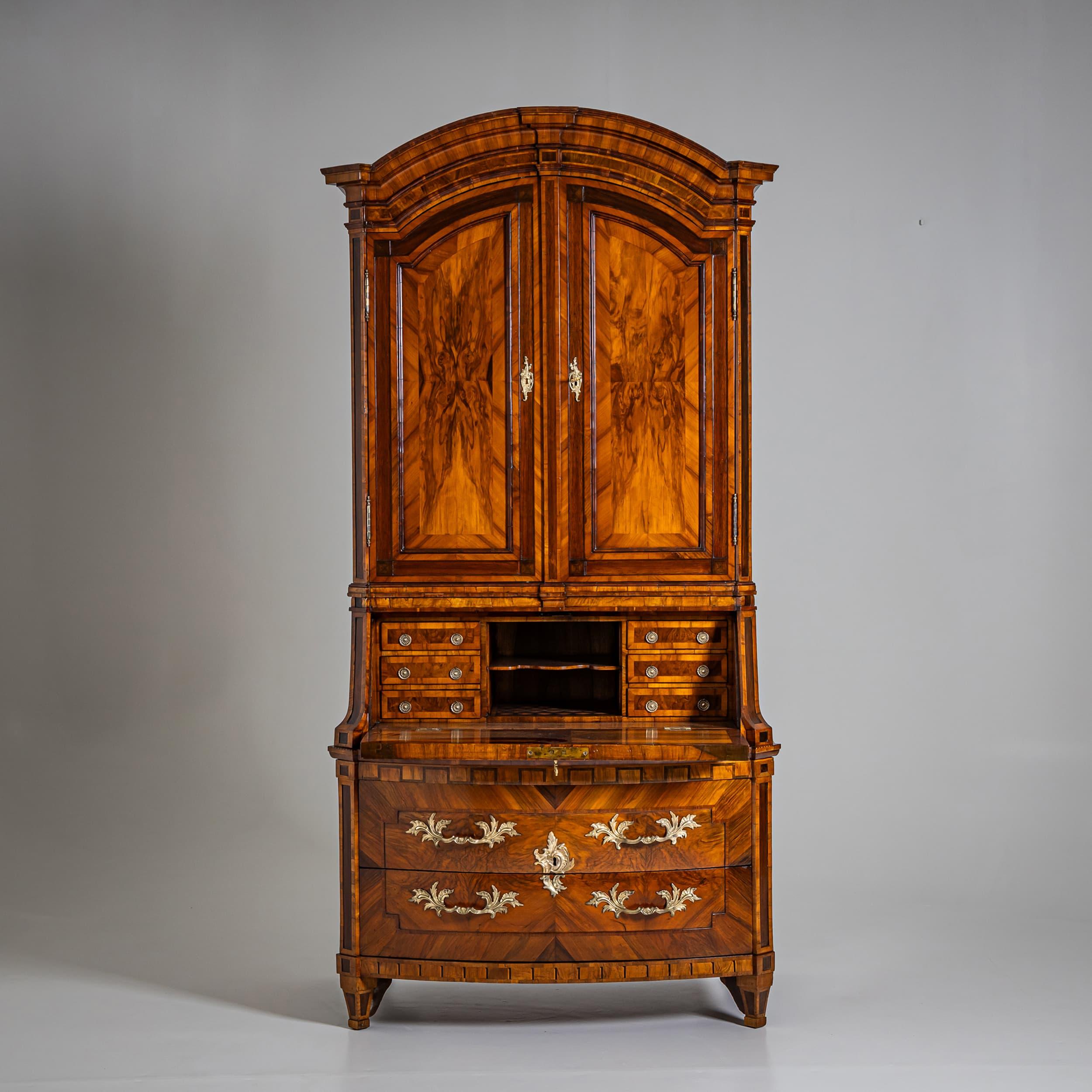 Impressive Baroque secretary from Dresden, featuring a two-drawer, slightly bombé commode base. Above it, a tall slant-front writing flap reveals a finely arranged interior with six small drawers and a shaped central shelf.

The upper section