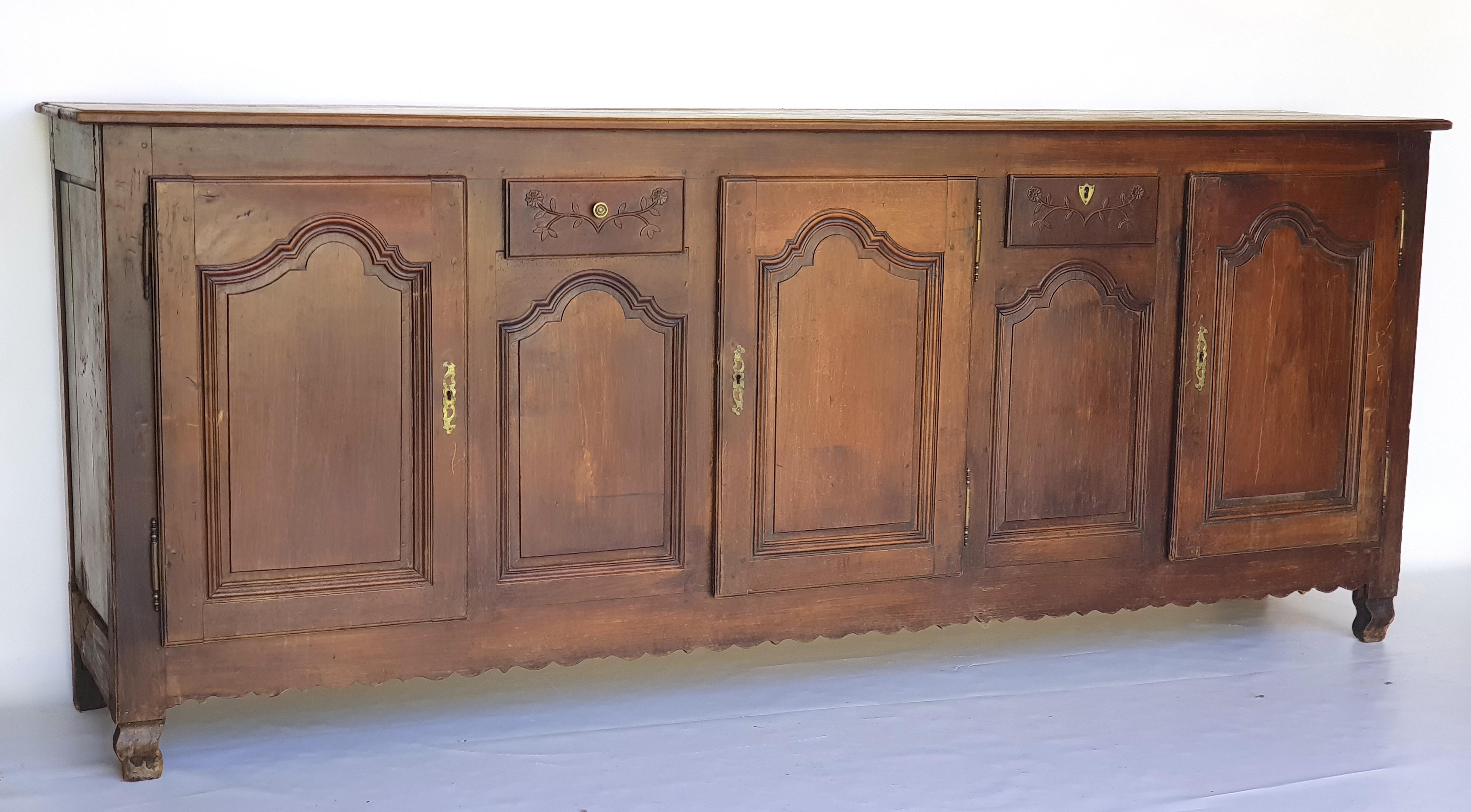Baroque Sideboard, Provence, France, 1780s. Made of walnut.

Laterally flared, curved legs. Frame cut out. Three panelled and profiled doors, in between a drawer with a fine floral ornament in bas-relief. Top made of wood. All locks and fittings
