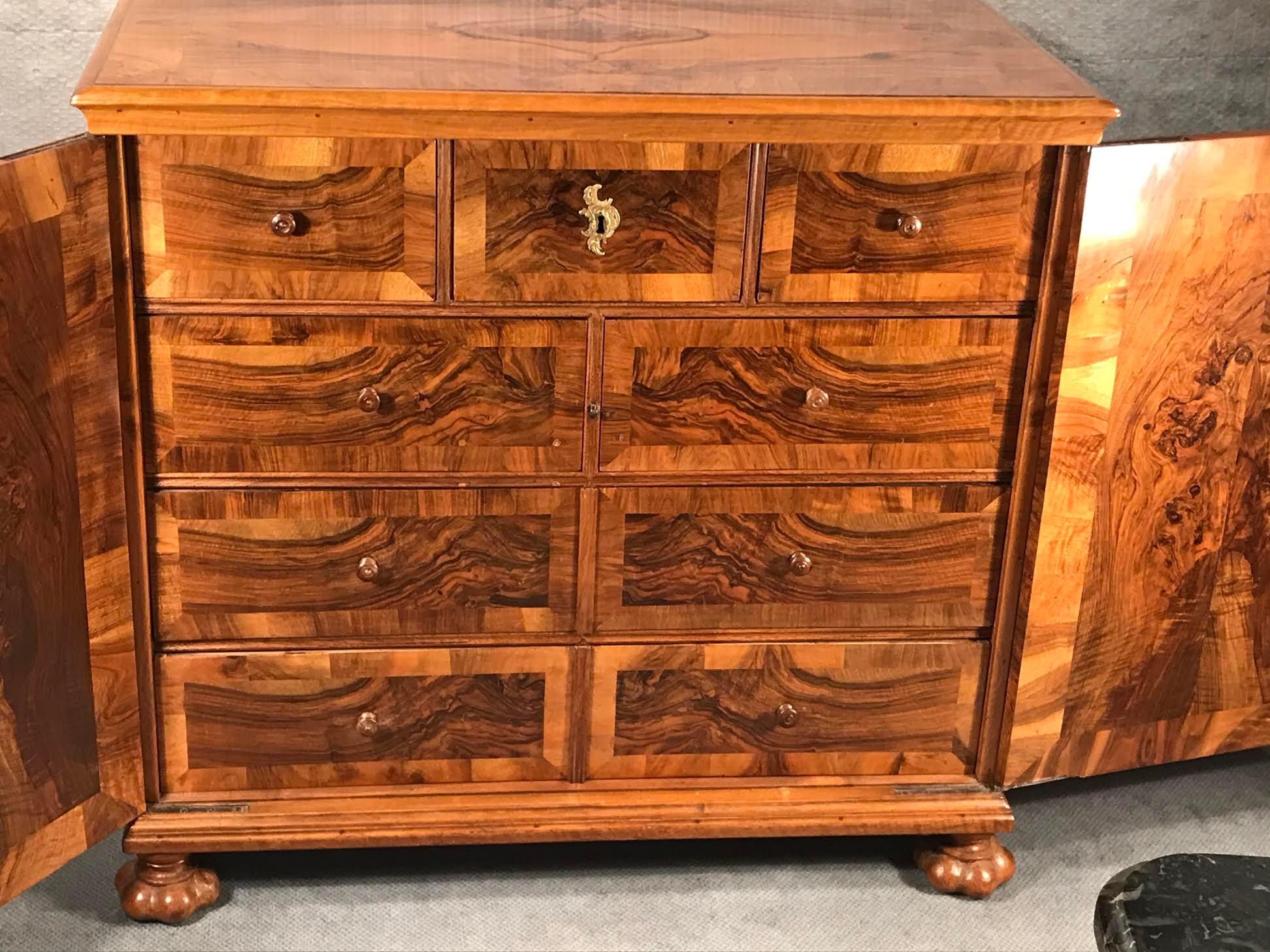 This Baroque cabinet dates back to the second half of the 18th century and comes from Switzerland. The cabinet has two doors, behind them are 9 smaller drawers. The drawers and the outside and inside of the doors have a gorgeous walnut veneer.