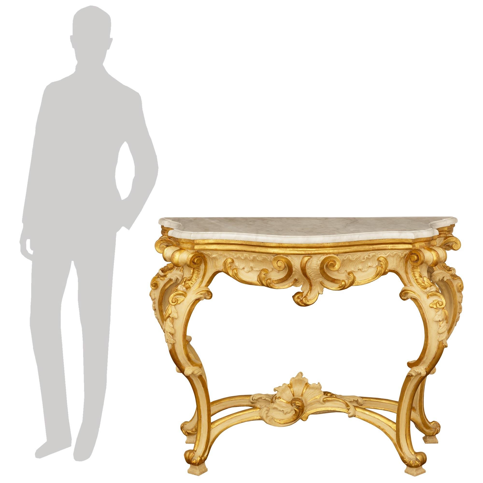 Una pareja sensacional y de lo más decorativa de consolas italianas del siglo XIX de madera patinada, giltwood y mármol blanco de Carrara, de estilo barroco. Este impresionante par de consolas exentas, con sus originales encimeras de mármol blanco