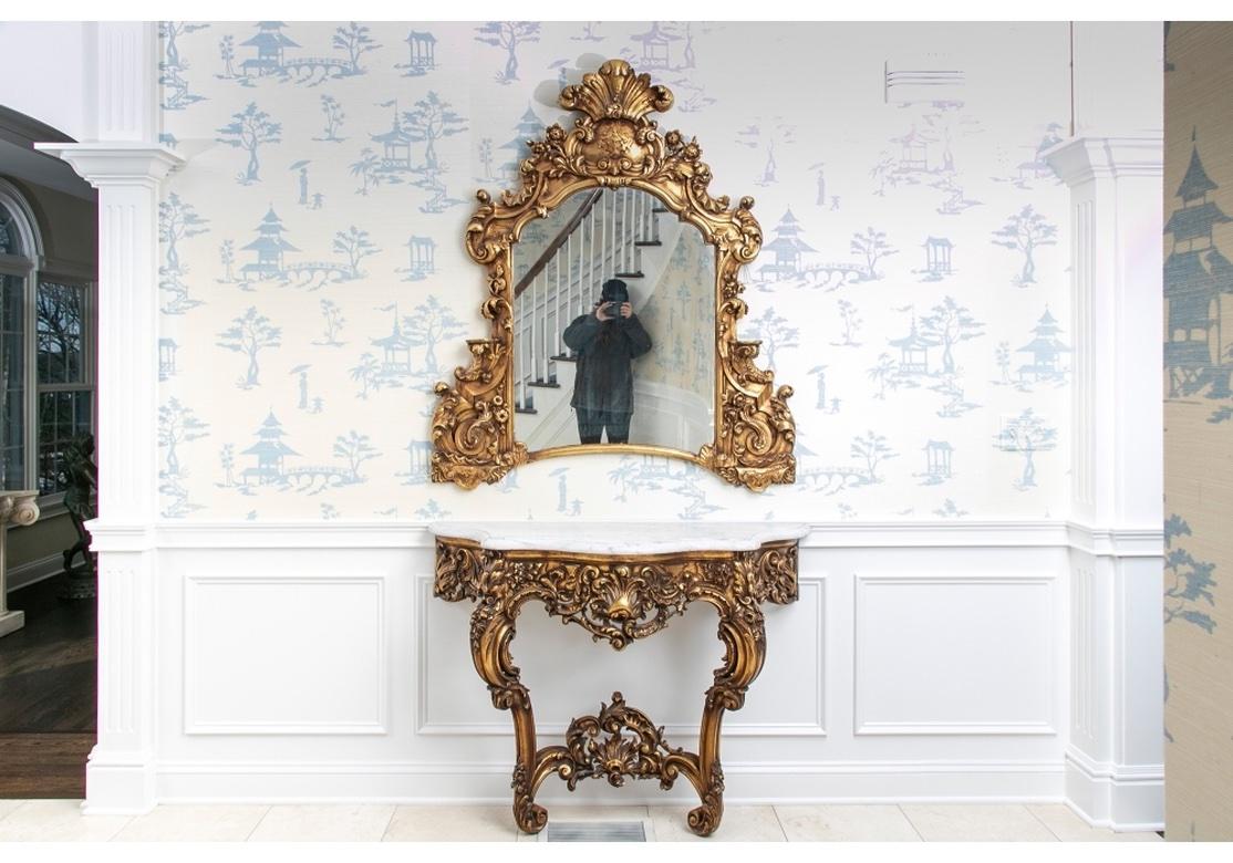 A very impressive ensemble including a large Gilt Wood Mirror and a Gilt Console with Marble Top. Provenance: the Dodge estate near Tuxedo Park, NY. Both in matching elaborate Baroque style. The mirror with feather crest, scrolled lower sides, and
