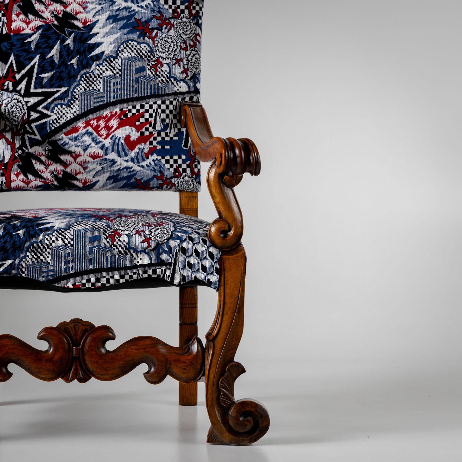 Large baroque-style nutwood armchair with high curved backrest and carved wooden frame with volute decoration from Italy. The armchair has a modern Japanese-style cover in blue, white and red. 
