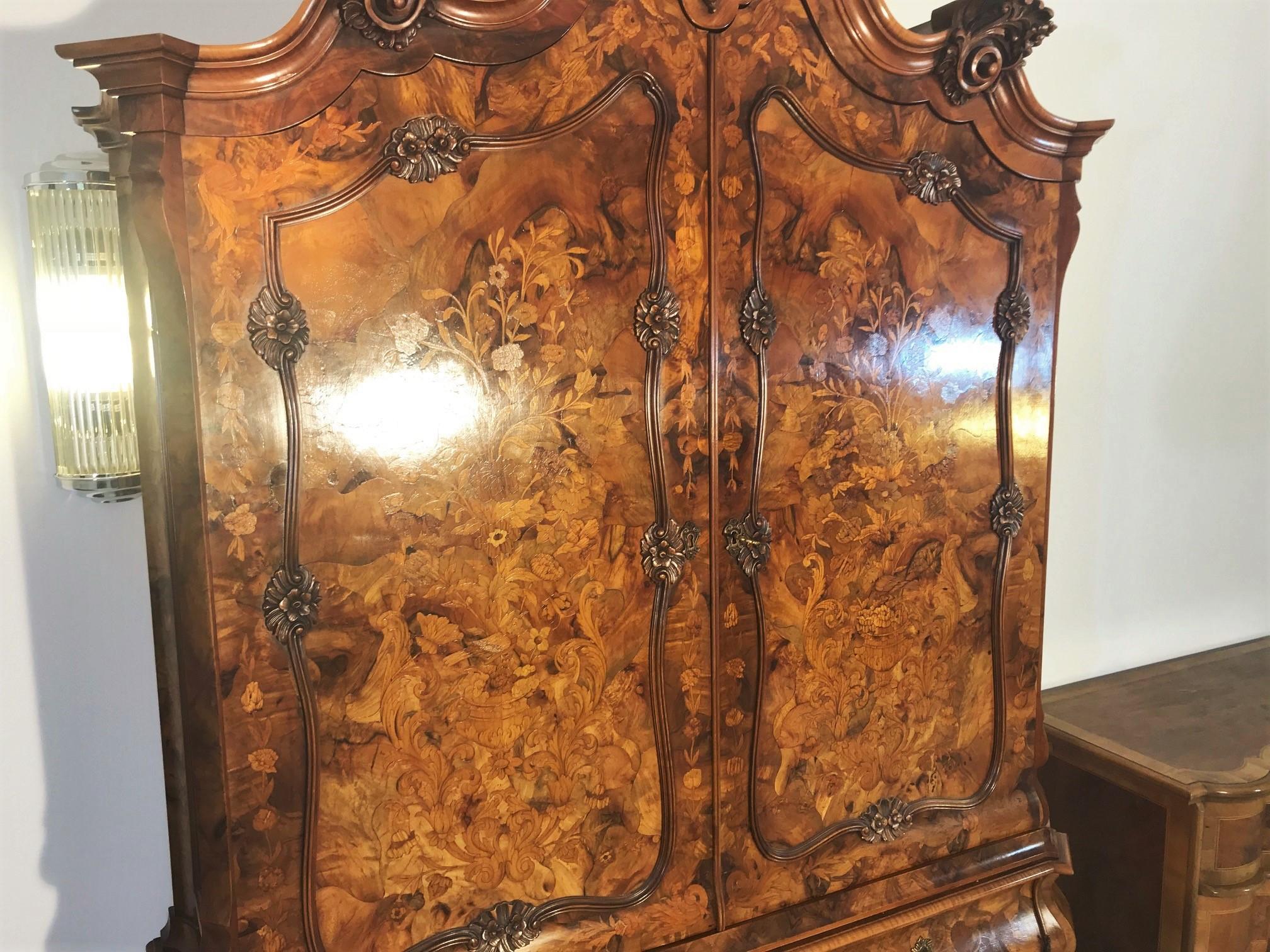 Walnut armoire or living room cabinet with beautiful floral ornamentations on the doors as well as curved drawers. Features an elegant crown with finely crafted details and matching claw feets. This unique masterpiece was build in the 1970s in