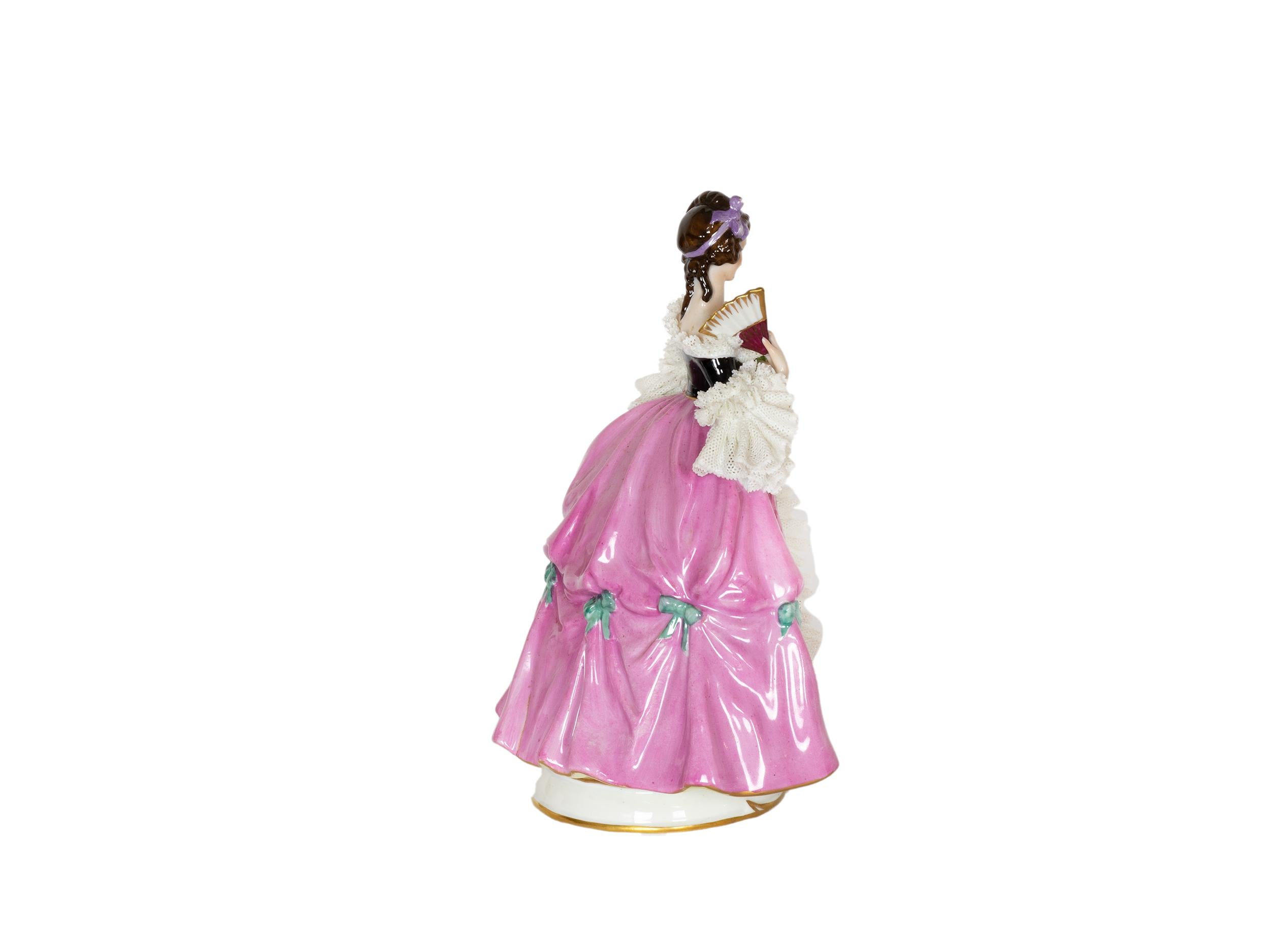 A Capadimonte's charming porcelain figure depicts a baroque styled woman dressed in pink and holding a fan.