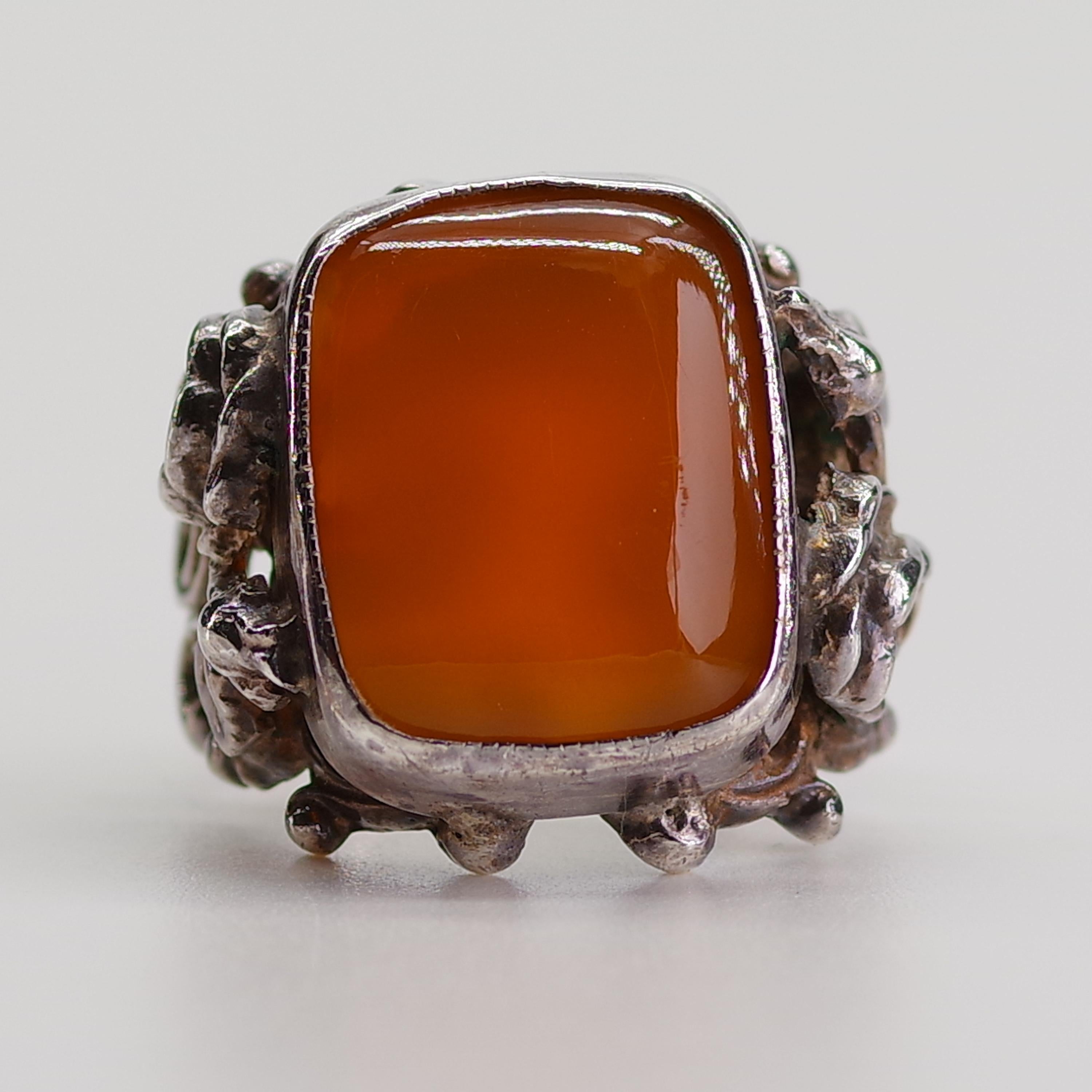 Created in London, England in 1896, this Carnelian ring features elaborately carved and pierced shoulders with a fanciful Baroque motif depicting roses, rosebuds, and leaves.  The rose, of course, is the official flower of England and has been