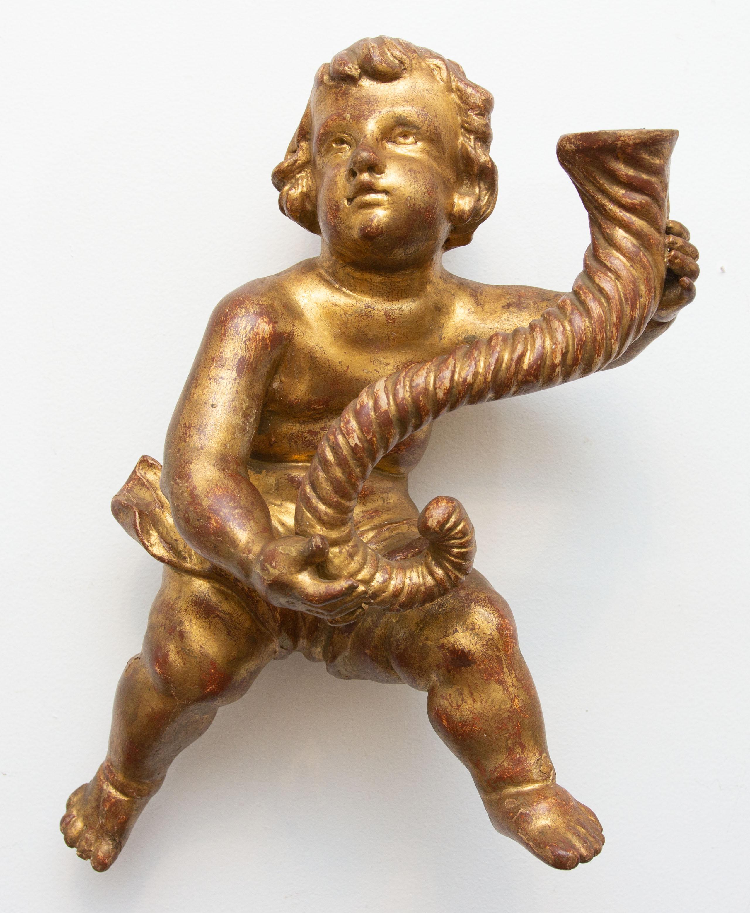 Pair of gilt and carved cherubs holding cornucopia. Gold leaf with red bole showing through, Italian, early 20th century. 
  