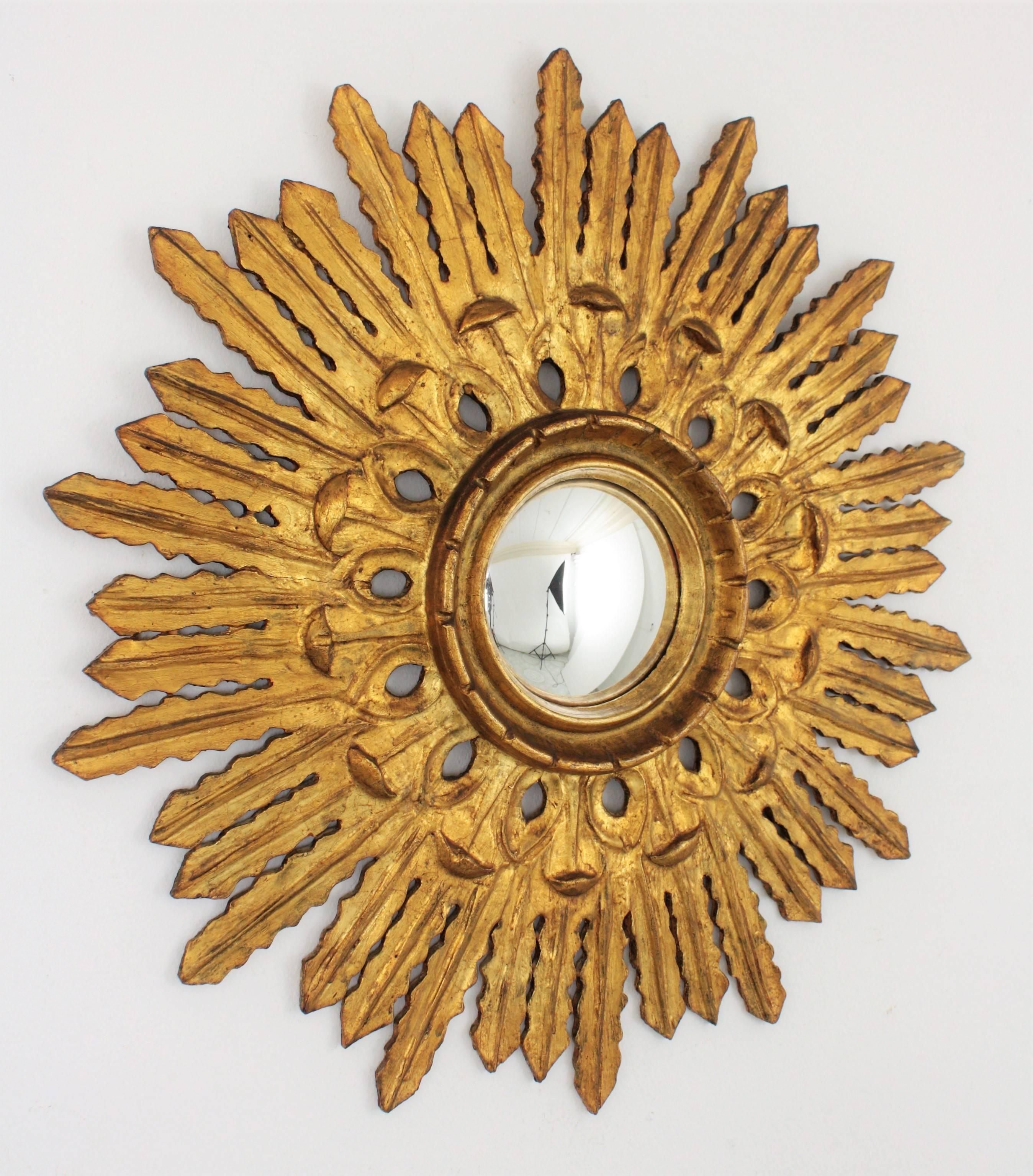 An exquisite finely carved Baroque style sunburst mirror with a carved filigrana decoration surrounding the convex glass. The sunburst shape and the lovely floral corolla surrounding the glass make this piece highly decorative. Wood covered with