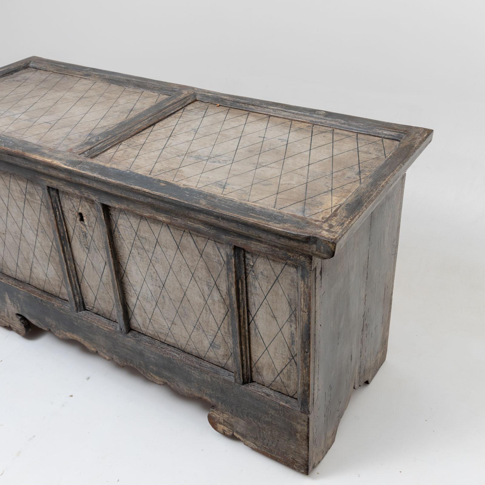 Grande cassapanca in abete con telaio e pannelli intagliati sulla parte anteriore e sul coperchio. Il dipinto grigio-beige con motivo a rombi è nuovo e presenta una patina antica. 