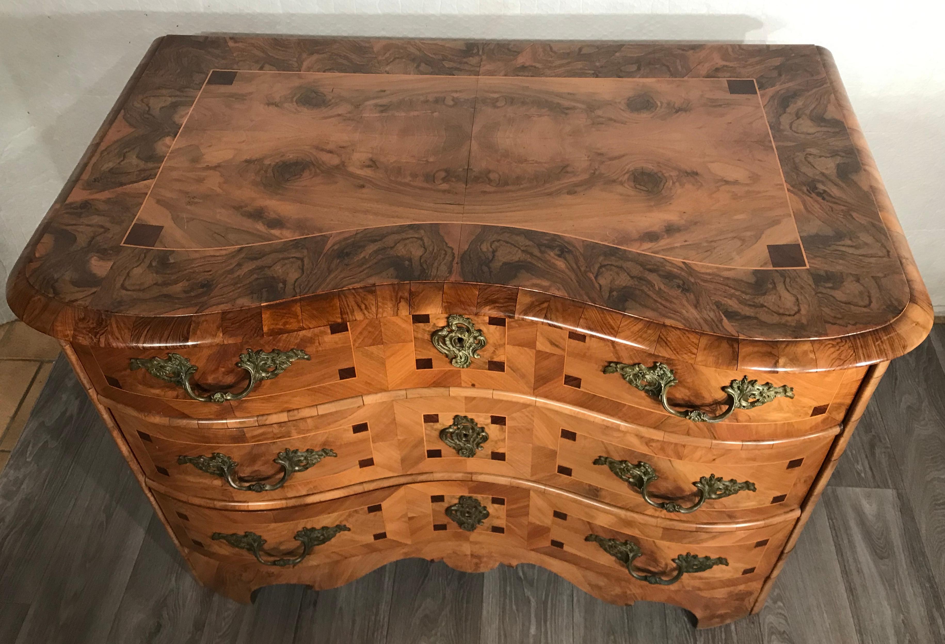 This pretty Baroque style chest of drawers dates back to circa 1850-1860. It has a beautiful walnut veneer with intarsia in mahogany. The three-drawer commode is in very good original condition and has its original bronze fittings.
It ships from