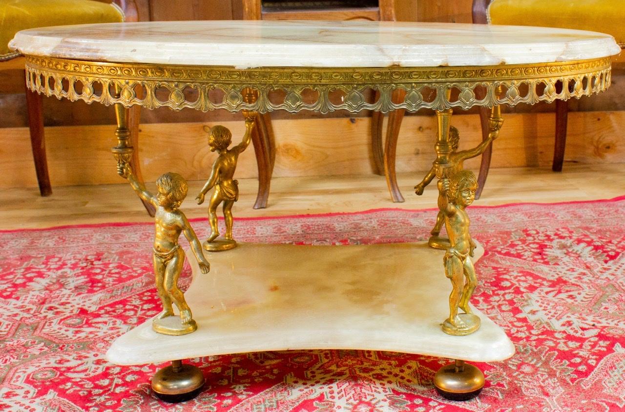 Very beautiful and elegant round table of living room of the middle of the XXth century of Baroque style. Composed of a white marble top supported by golden brass putti sculptures. Four putti are arranged on each side of the table known to be angels