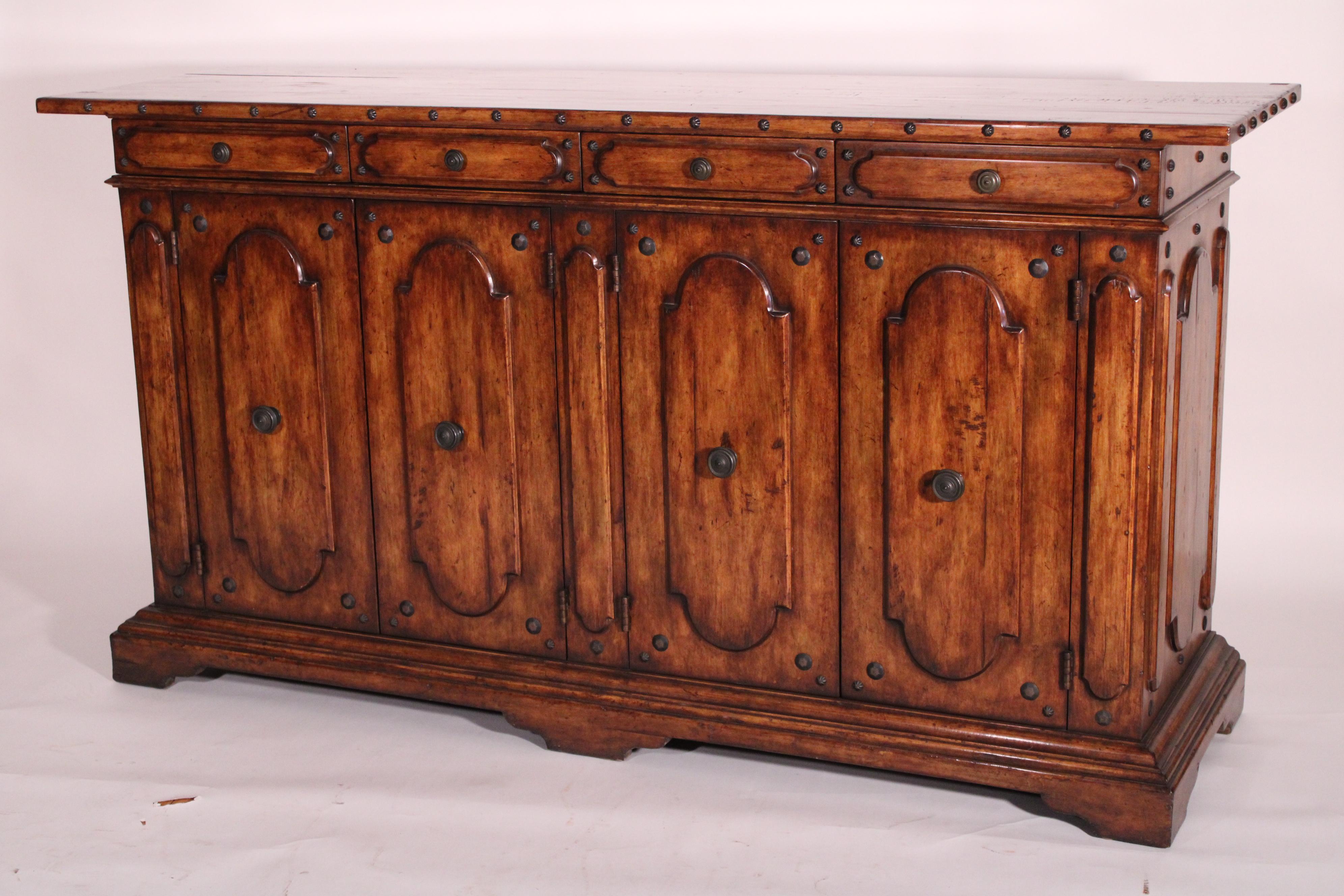 Italian baroque style hard wood credenza, late 20th century. With a rectangular top with brass studs on front and side edges, 3 frieze drawers with brass pulls and brass studs, 3 cupboard doors with brass pulls and brass studs, nicely paneled sides,
