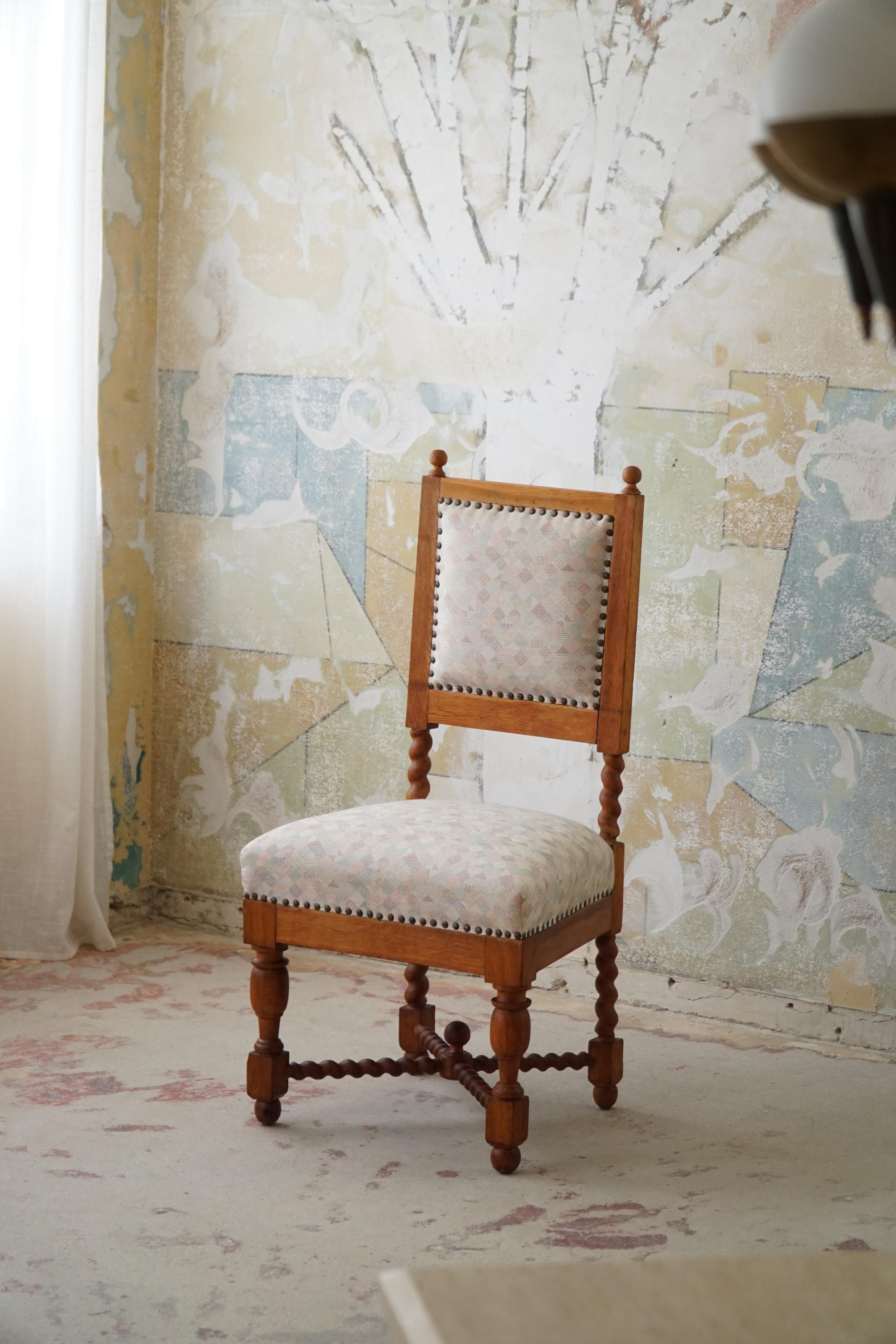 Exquisite and timeless, the Baroque-style English chair with barley-twisted legs in oak from the 1920s encapsulates the grandeur and craftsmanship of a bygone era. This chair is a testament to the opulence and attention to detail that defined the