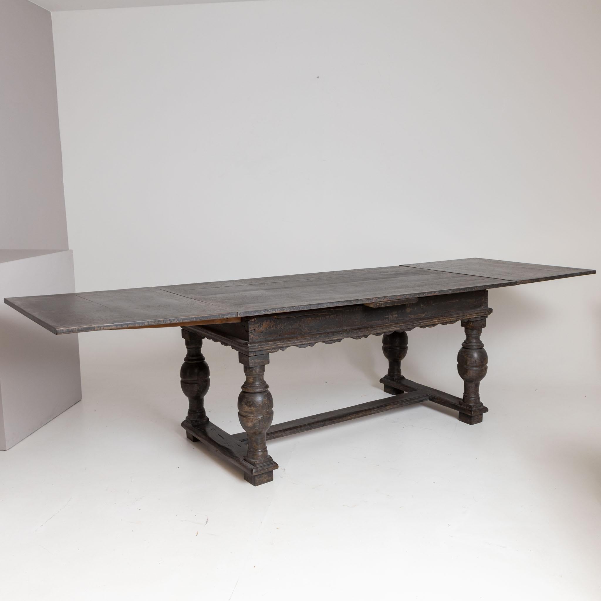 Large dining table with curved frame and baluster legs and H-shaped bracing. The table has a maximum dimension of 74.5 x 296 x 90 cm. The gray setting is new and has been decoratively rubbed through.