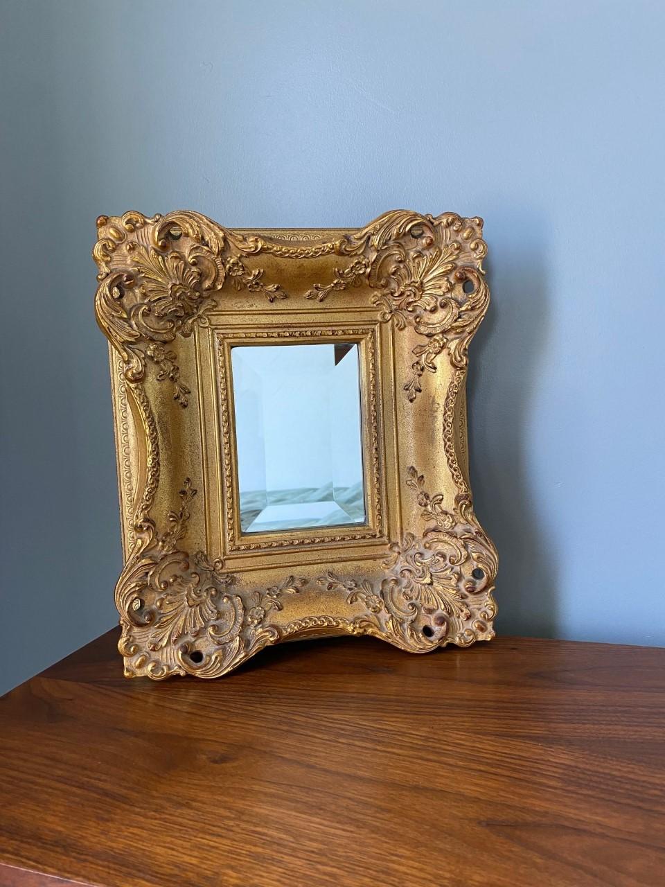 Beautifully ornate and gold accent mirror. This piece brings light and shine to any corner or space. The intricate and captivating wood frame envelops a beveled mirror with beautiful contrast. Classic and unexpected at the same time. An incredible