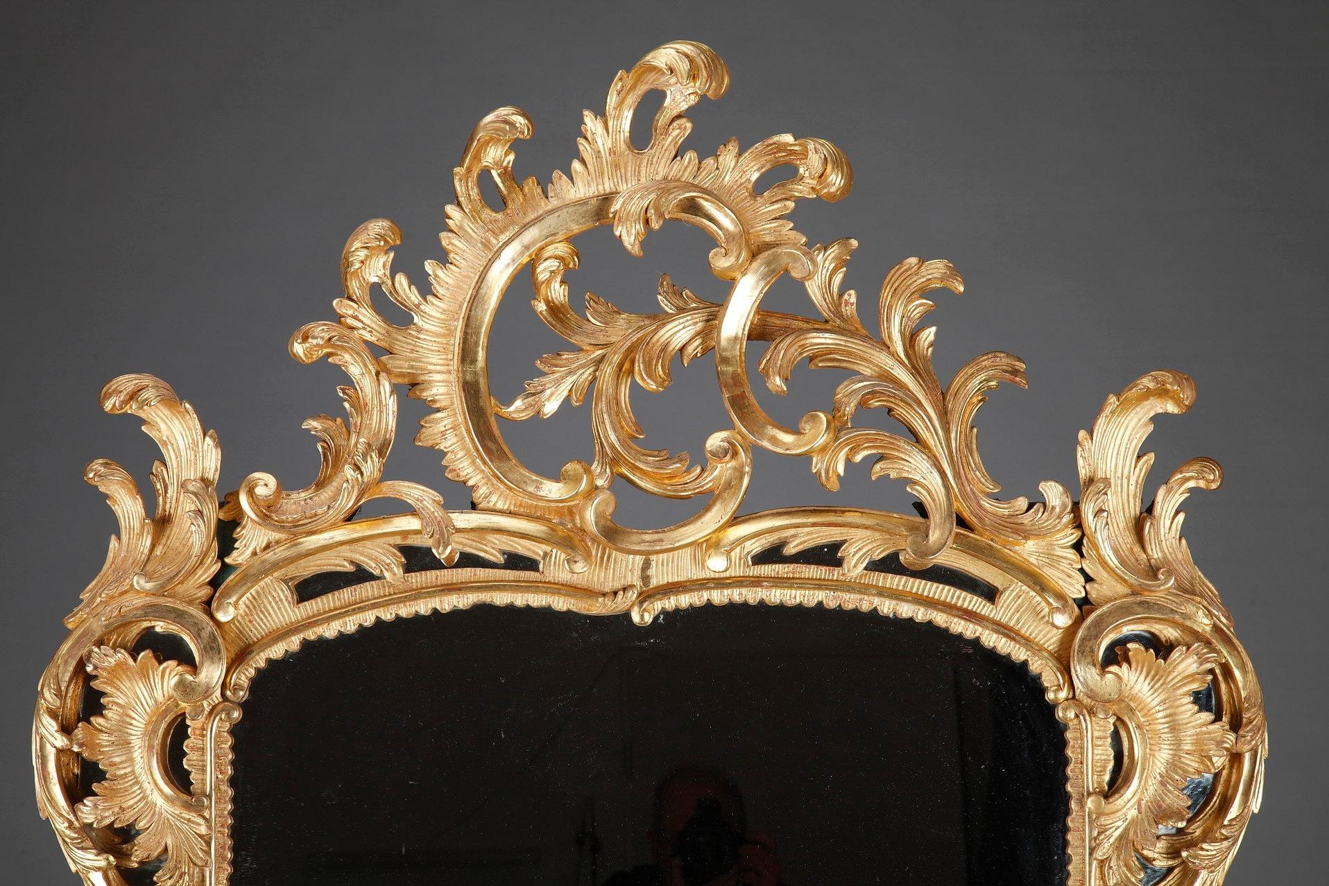 Monumentaler, im opulenten Barockstil gefertigter Spiegel. Der Spiegel hat einen ondulierenden, aufwändig geschnitzten Rahmen aus Goldholz, der reich mit Akanthusblättern, asymmetrischen Blattranken und Rocaille-Akzenten verziert ist. Zeitraum