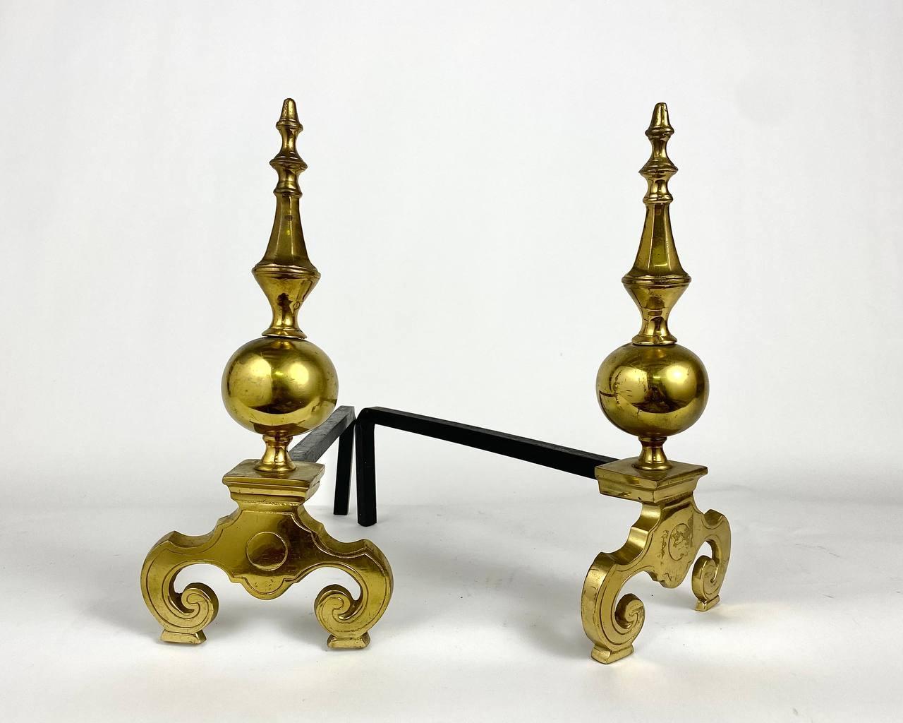 Pair of chased brass and cast iron baroque style mantelpieces from France, circa 1950s.

The ball-shaped uprights with fleurons enhance the fleur-de-lys patterned legs.

These elegant and practical andirons allow air to reach the fire from all sides