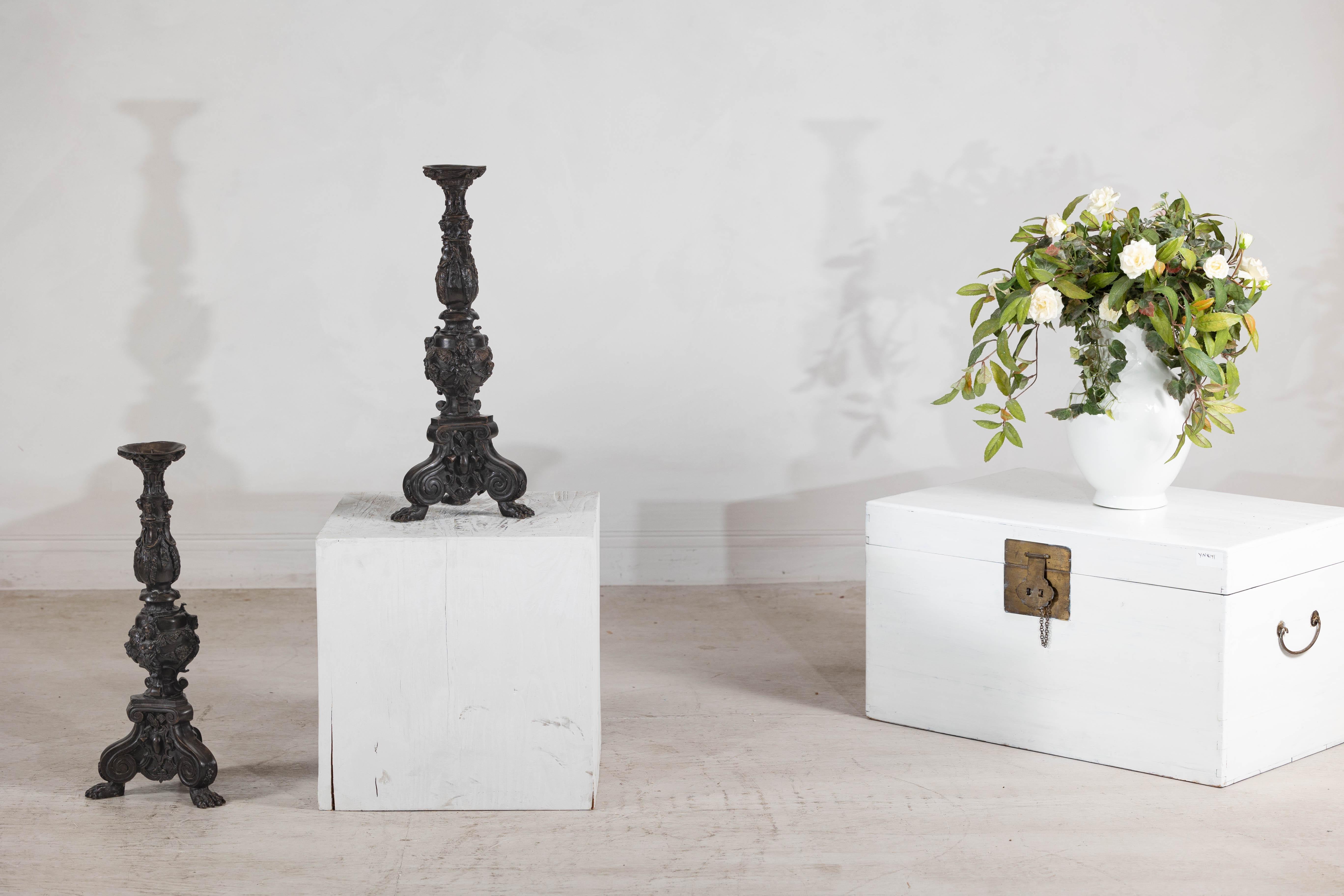 Coppia di candelieri in metallo in stile barocco con motivi di cherubini e ghirlande. Evocando la drammaticità e l'intricatezza del design barocco, questa coppia di candelabri vintage in metallo costituisce un'audace dichiarazione decorativa. La