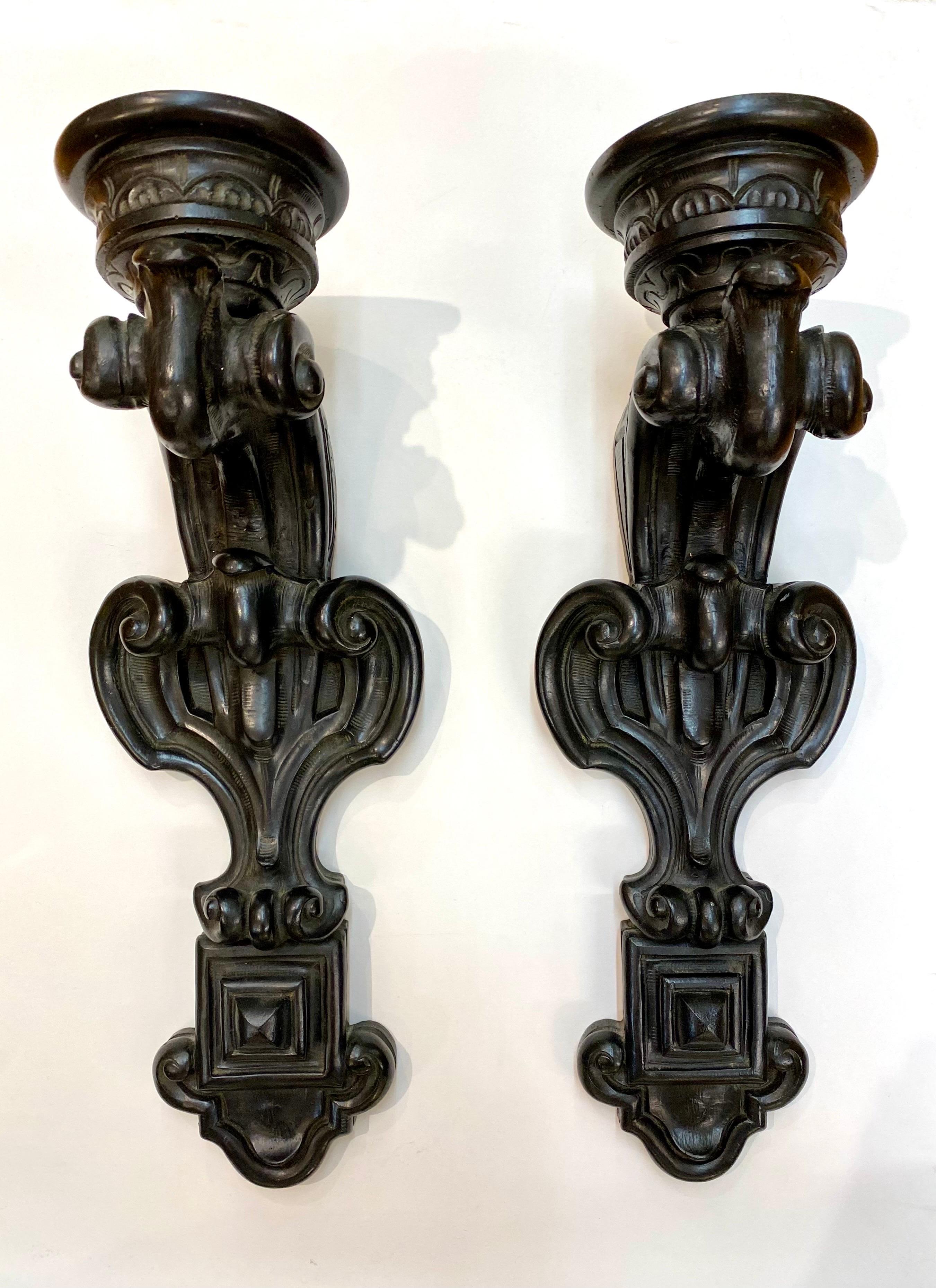 A wonderful and large pair of cast resin with antique black finish candle holder sconces in the Baroque style. Each has a 1” recesses hole 3” in diameter to fit a large column candle.

Left sconce 7 6/8” W x 21.75”H x 8”D
Right sconce 7.25”W x