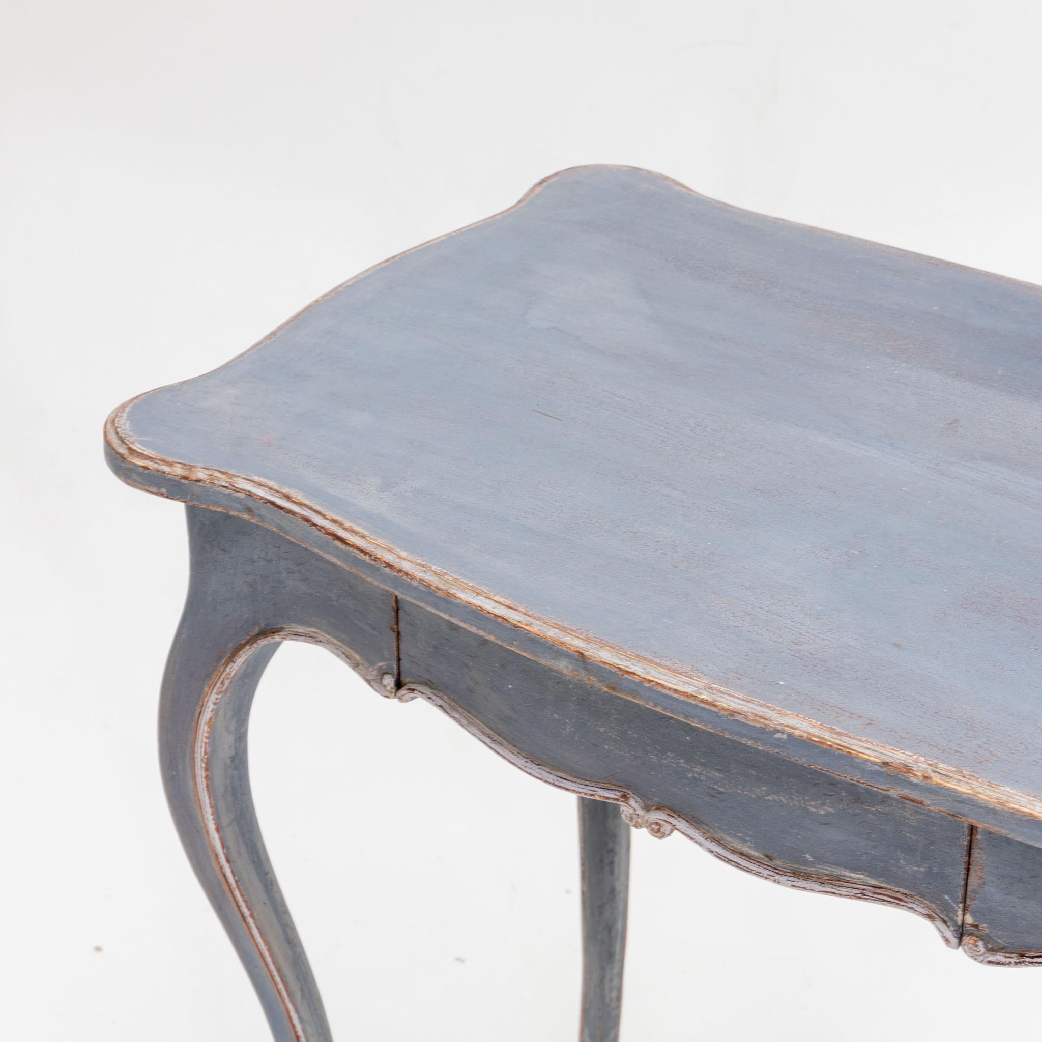 Small side table in softwood with one drawer and high elegant S-legs. The frame is multi-curved like the tabletop. The light blue setting is new and has a decorative patina.