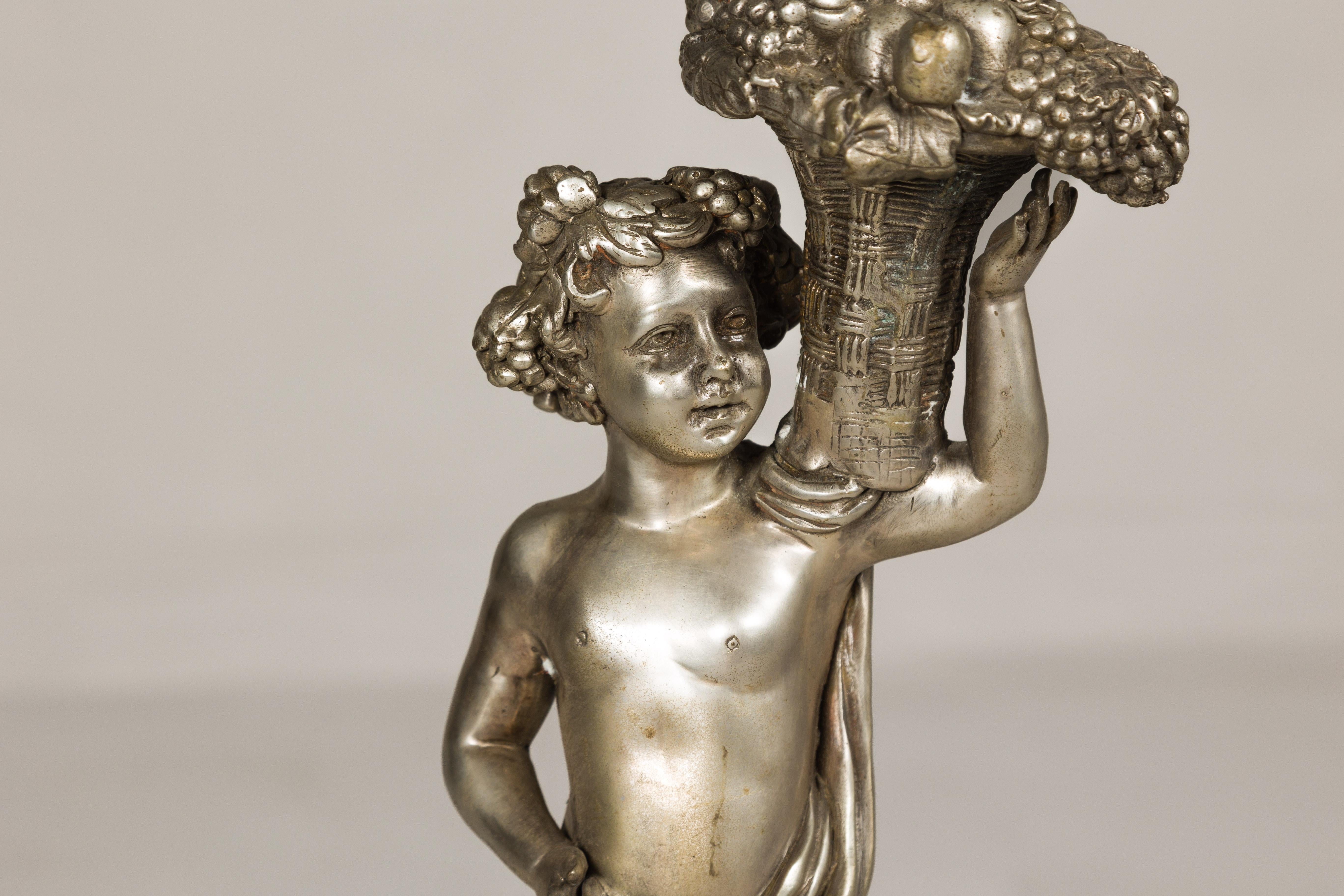 Argenté Statuette en bronze argenté de style baroque d'un putto transportant un panier de fruits en vente