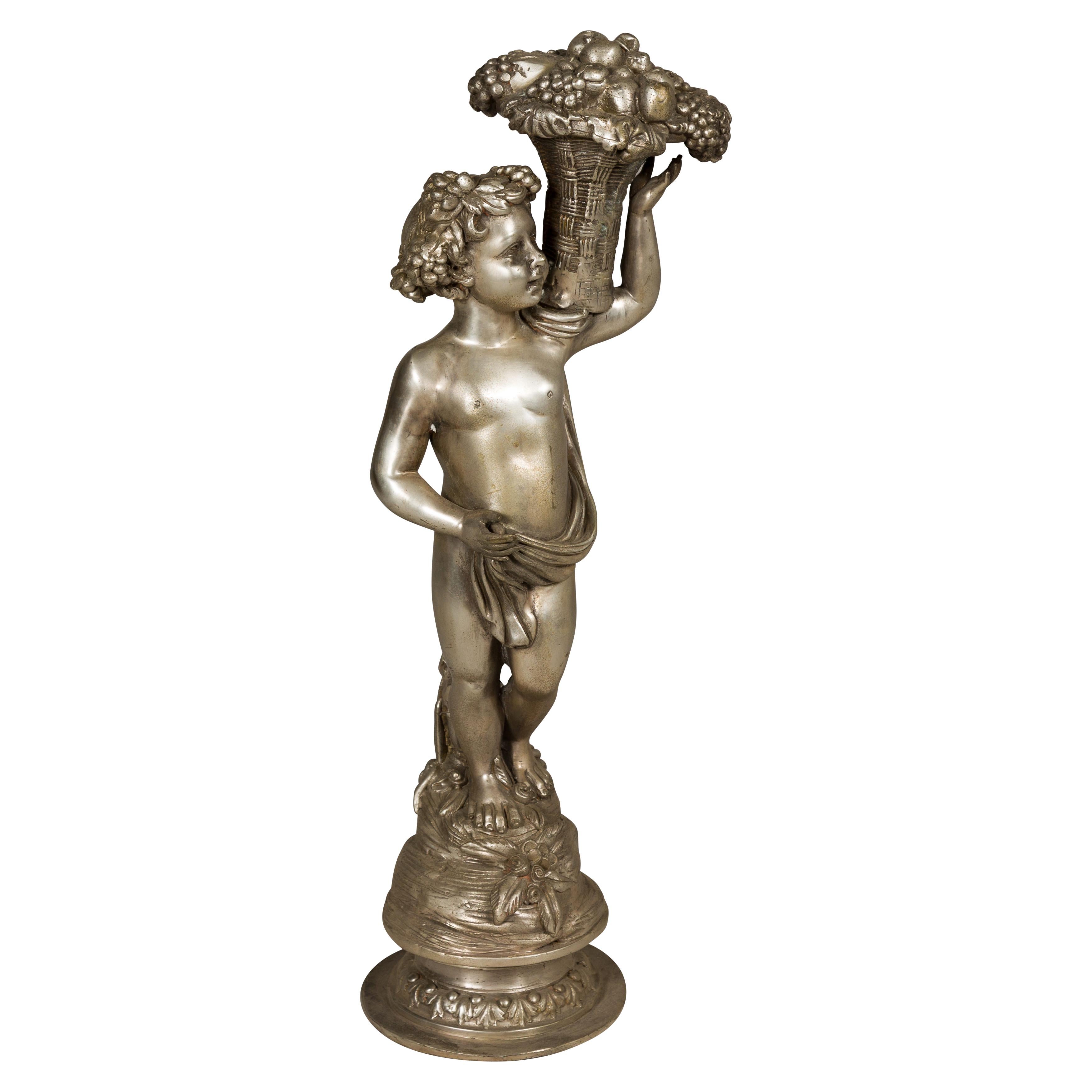 Statuette en bronze argenté de style baroque d'un putto transportant un panier de fruits en vente