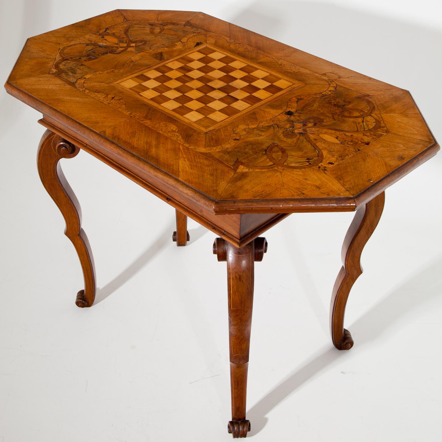 Baroque table standing on voluted legs with thread inlays, made out of walnut. The octagonal tabletop is inlayed with a chessboard surrounded by scrollwork inlays.