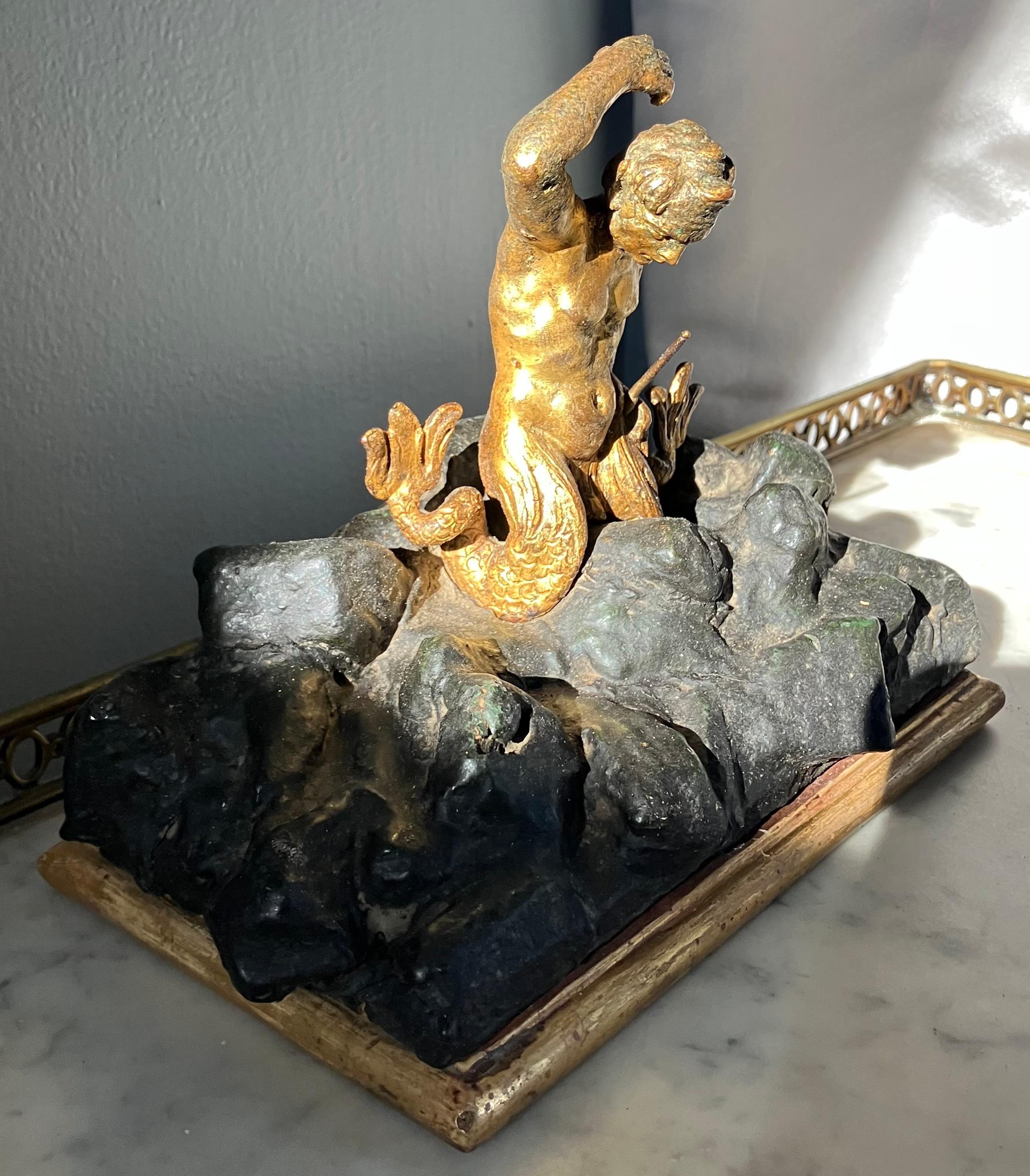 Escultura barroca de tritón. Antigua escultura del dios marino tritón de hierro dorado de finales del siglo XVII, finamente fundida, con la cola partida a horcajadas sobre las 