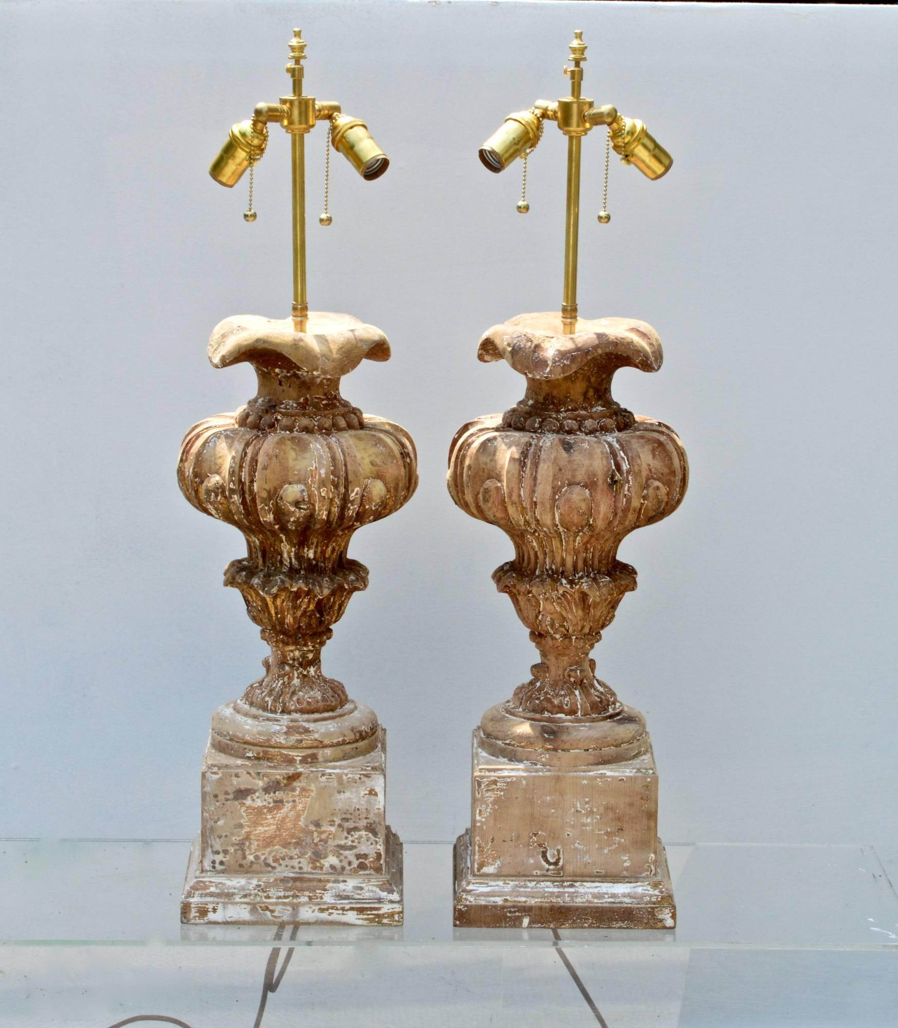 A large-scale pair of baroque inspired table lamps of carved pine having a bleached and distressed finish. Newly wired with brass double socket clusters and brown cloth wrapped cords, the lights will add drama and flare to any room in which they are