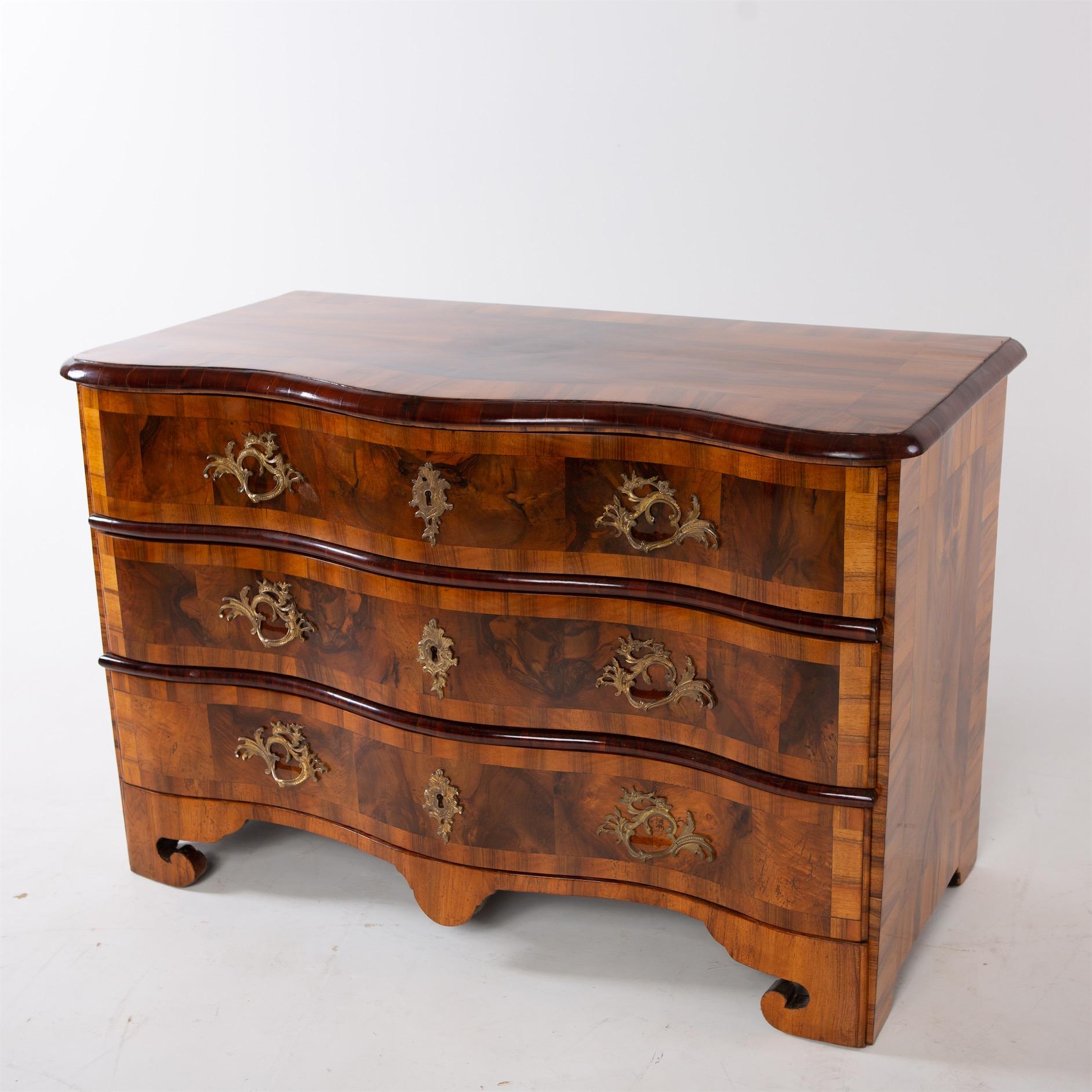 Three-drawer Baroque chest of drawers on bracket feet, with a wavy front and moving Rococo fittings. Very beautiful walnut veneer, expertly refinished and hand polished.
  