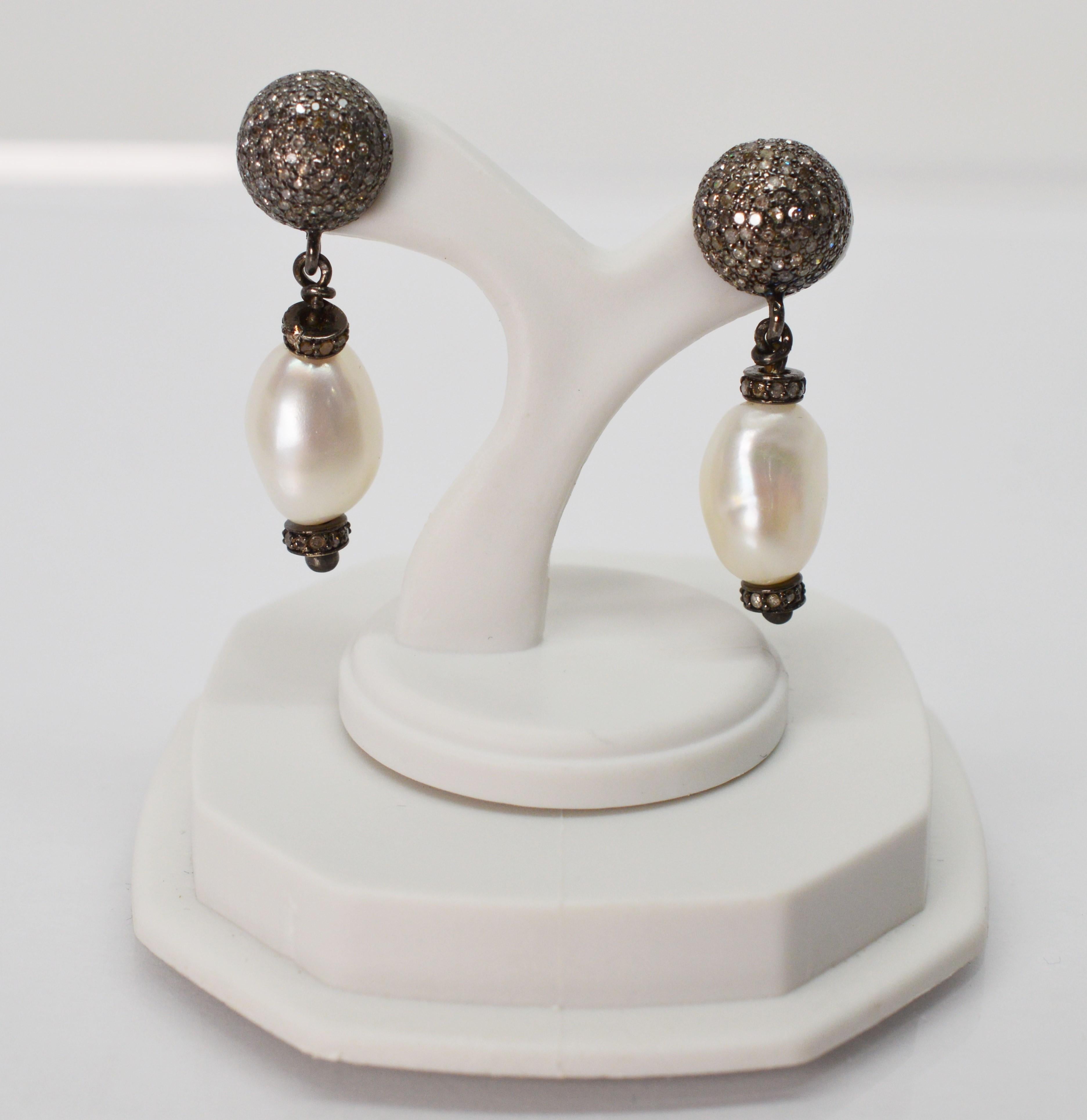 The natural beauty of baroque white Akoya pearls are displayed by these elegant drop earrings. Post style for pieced ears with a toned silver and diamond stud, the singular pearls measuring 7.25mm x 12.25mm dangle approximately one inch from the