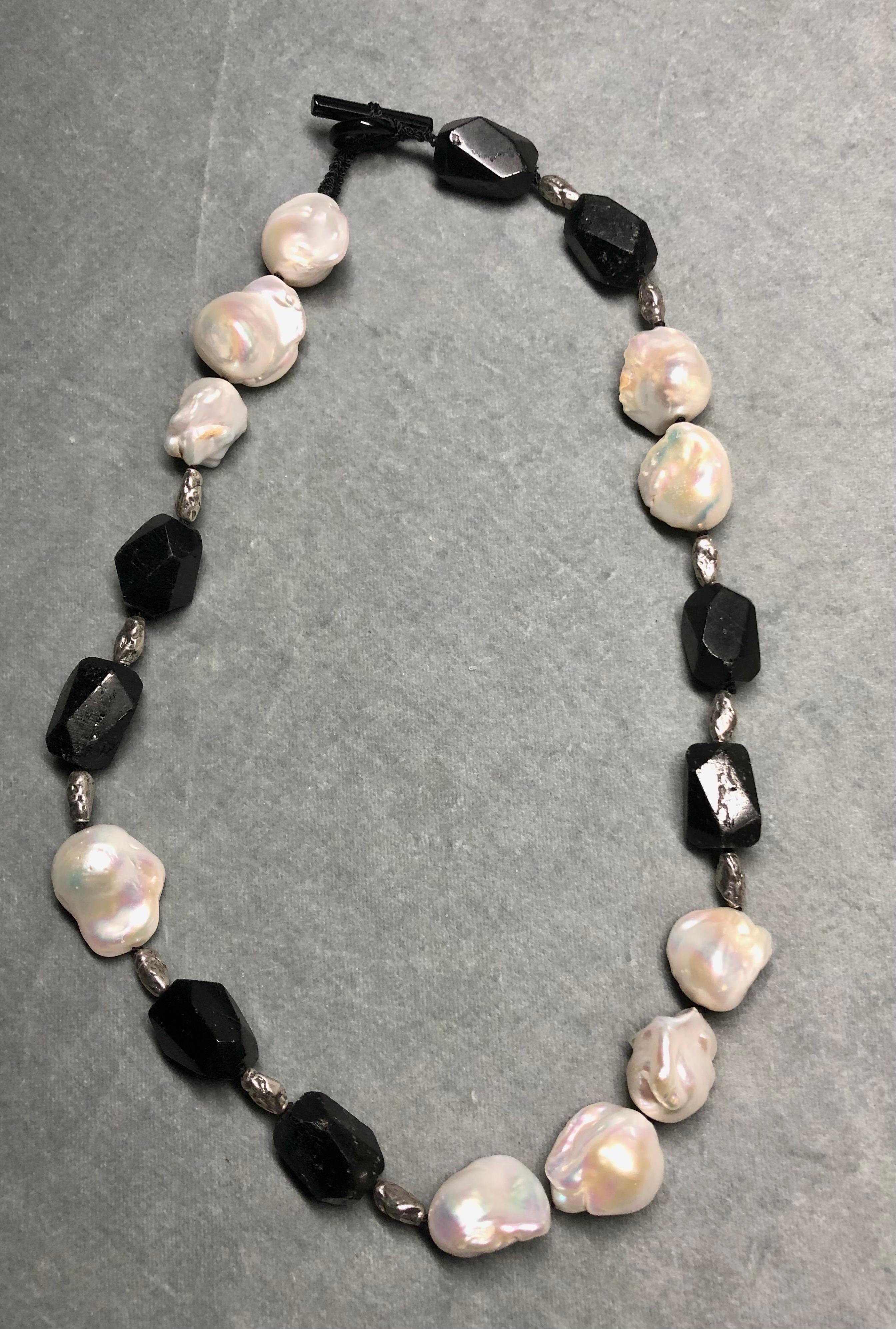Single strand necklace. Large baroque white freshwater pearls, black tumbled tourmaline nugget beads. Interspersed with pure silver nugget beads. Finished with black onyx toggle clasp. 