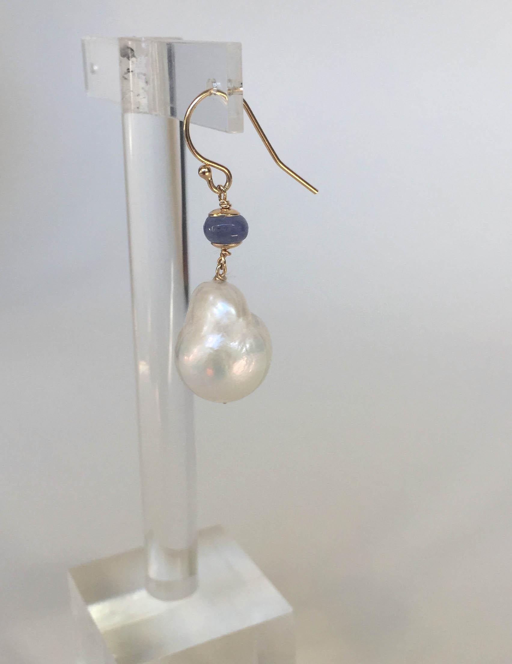 These baroque white pearl and tanzanite earrings with 14k yellow gold hooks and wiring are a beautiful take on classic white earrings. At 1.5 inches long these earrings drape the face gracefully. The 14k yellow gold hook and wiring accent the blue